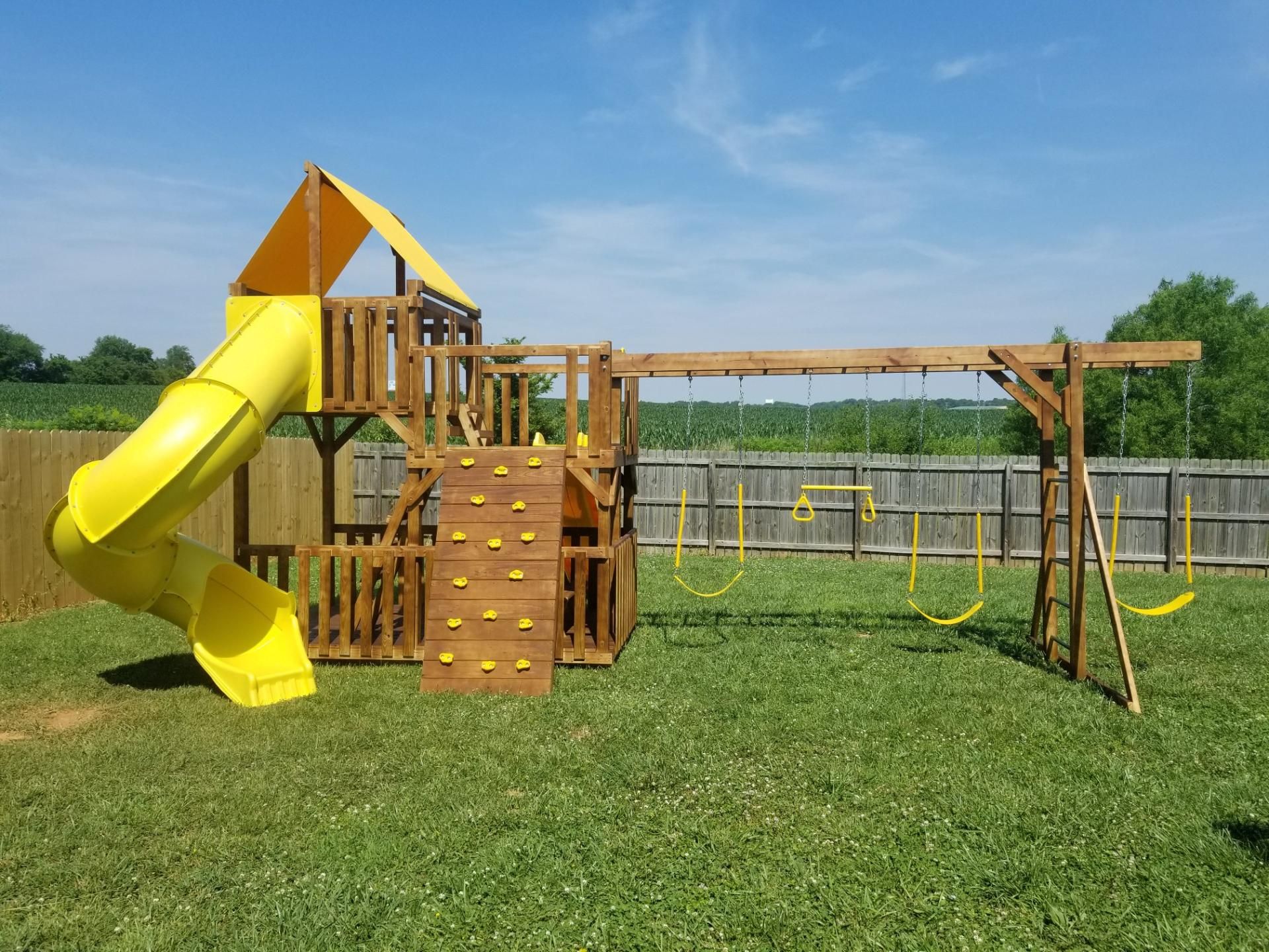 A wooden playground with a blue slide and swings