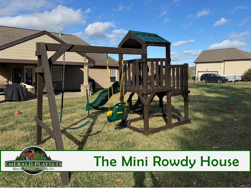 A brown wooden swing set and playhouse on a grassy lawn under a blue sky.