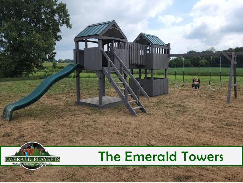 Playground set, gray wooden structure with slide, stairs, and swing set in a grassy yard.