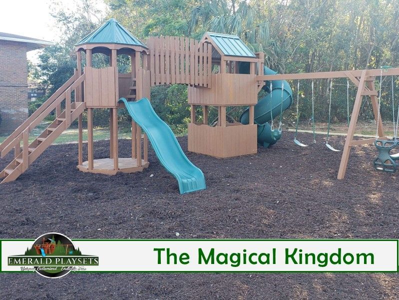 Playground with a slide, towers, and swings set on mulch.
