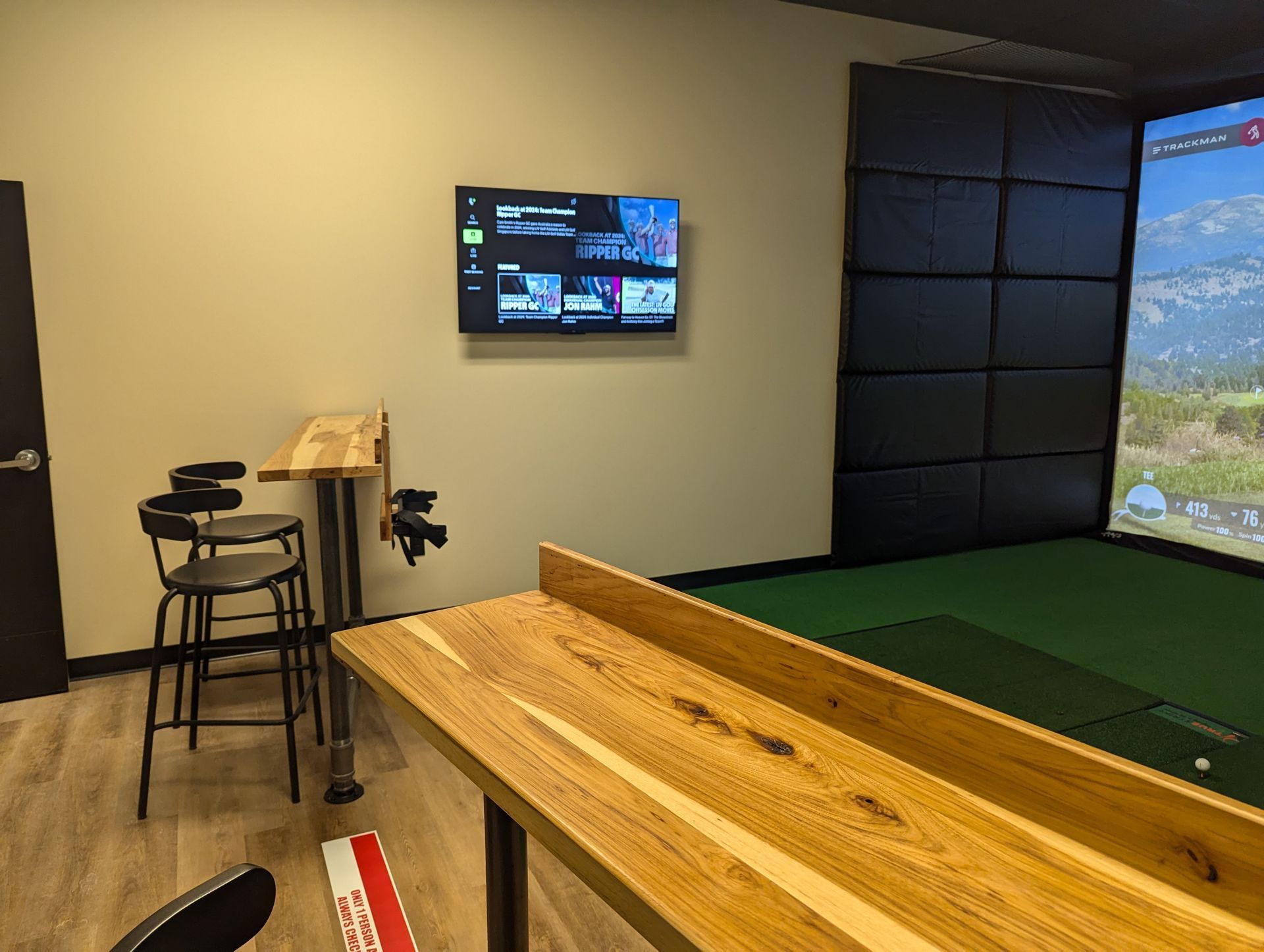 A room with a table and chairs and a television on the wall.