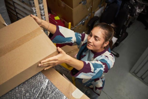 A woman storing boxes in a storage unit.