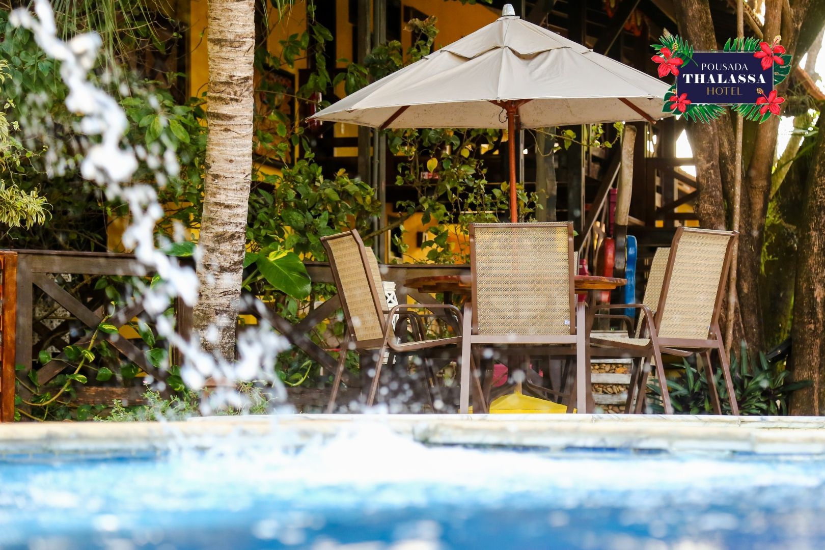 Uma piscina com uma mesa e cadeiras sob um guarda-sol