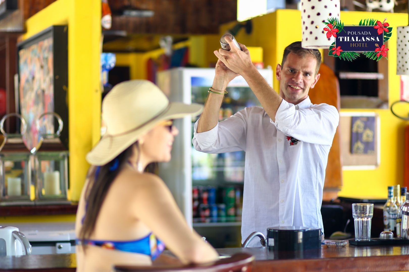 Um homem está preparando uma bebida para uma mulher de biquíni em um bar.