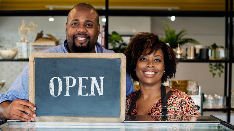 A man and a woman are holding a sign that says `` open ''.