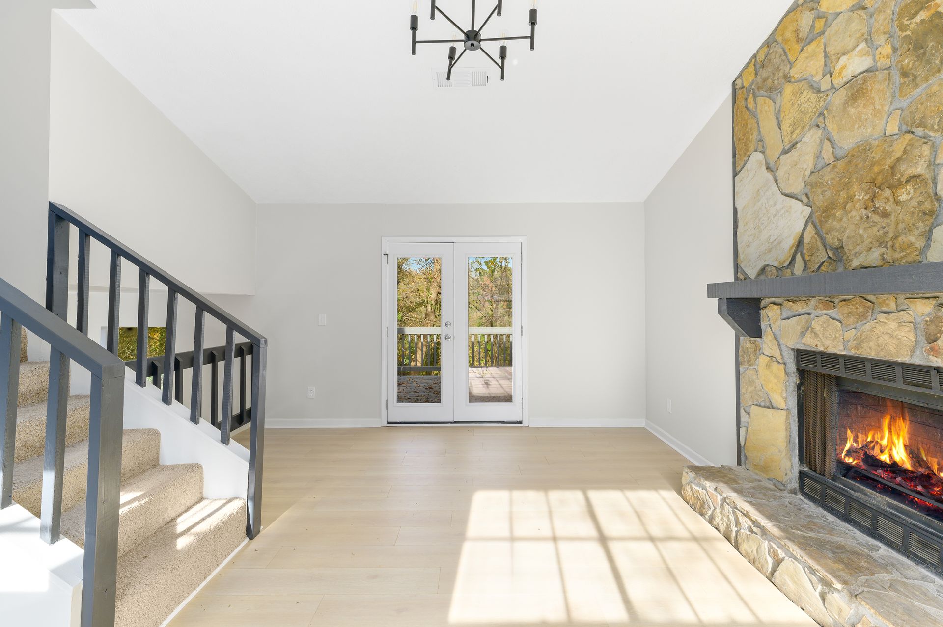 An empty living room with a fireplace and stairs.