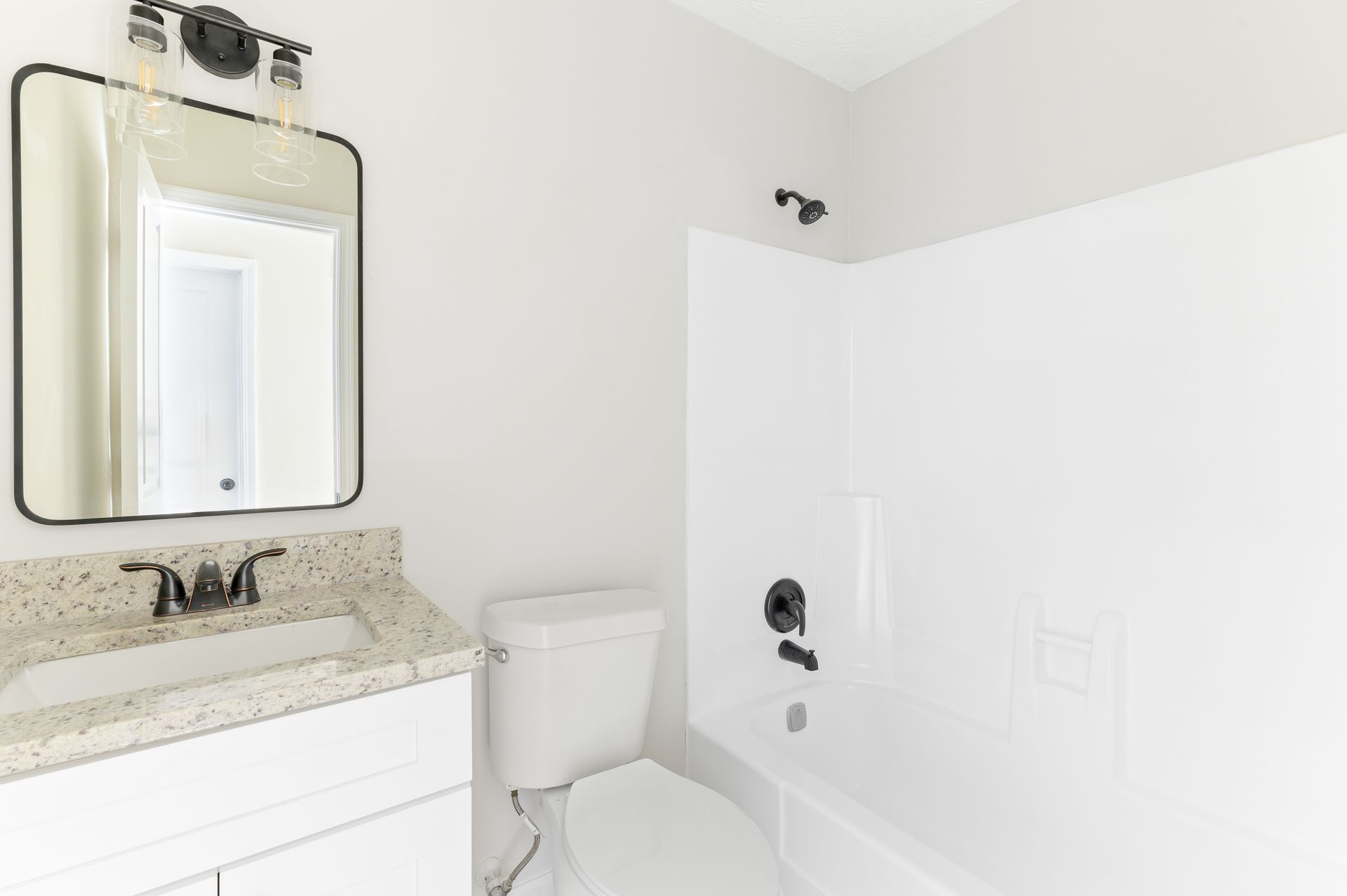 A bathroom with a toilet , sink , mirror and bathtub.