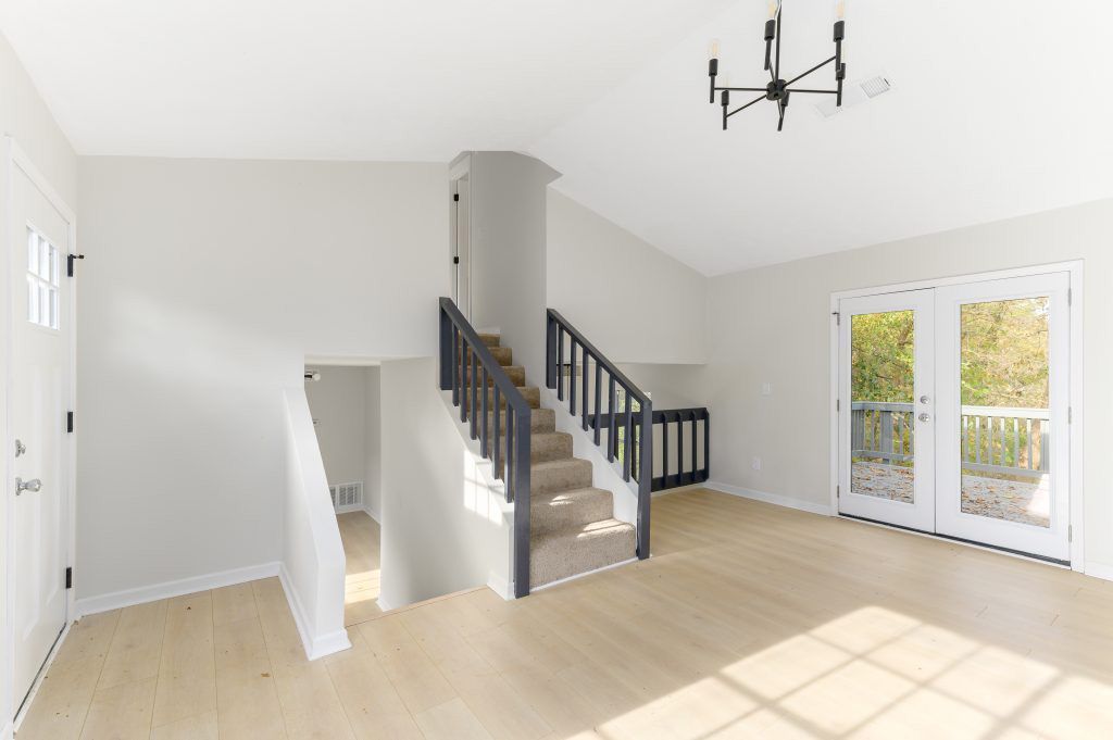 An empty living room with stairs leading up to the second floor.