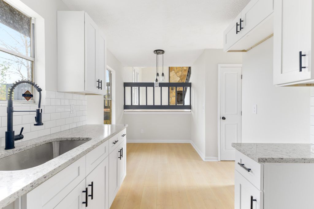 A kitchen with white cabinets , granite counter tops , and a sink.