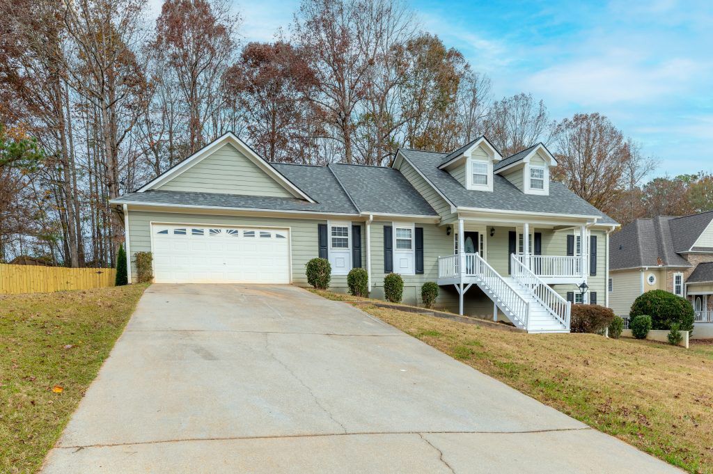A large house with a driveway leading to it and trees in the background.