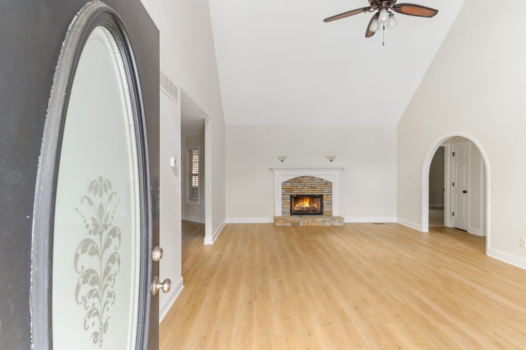 An empty living room with a fireplace and a ceiling fan.