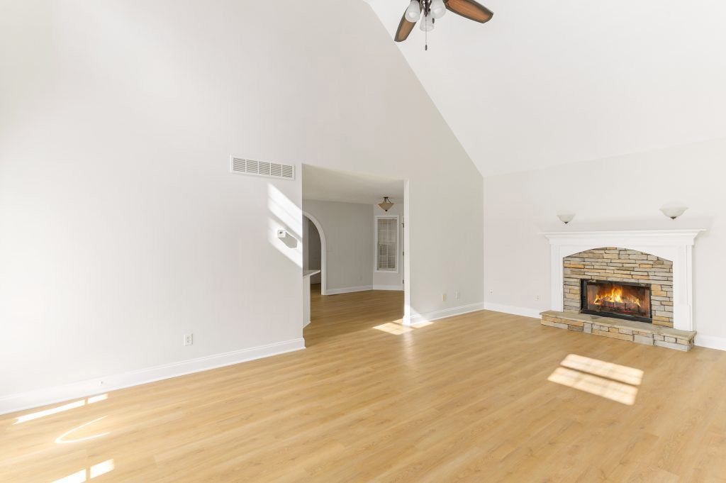 An empty living room with hardwood floors and a fireplace.
