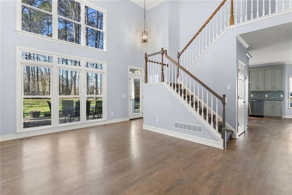 An empty living room with a staircase and lots of windows.