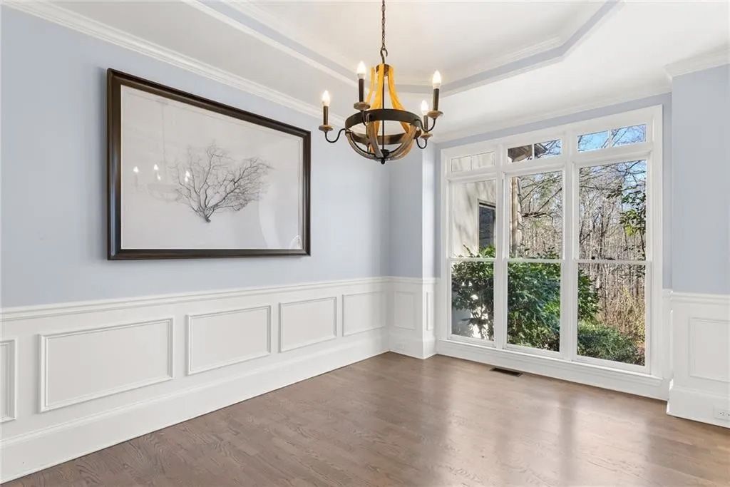 An empty dining room with a chandelier and a picture on the wall.