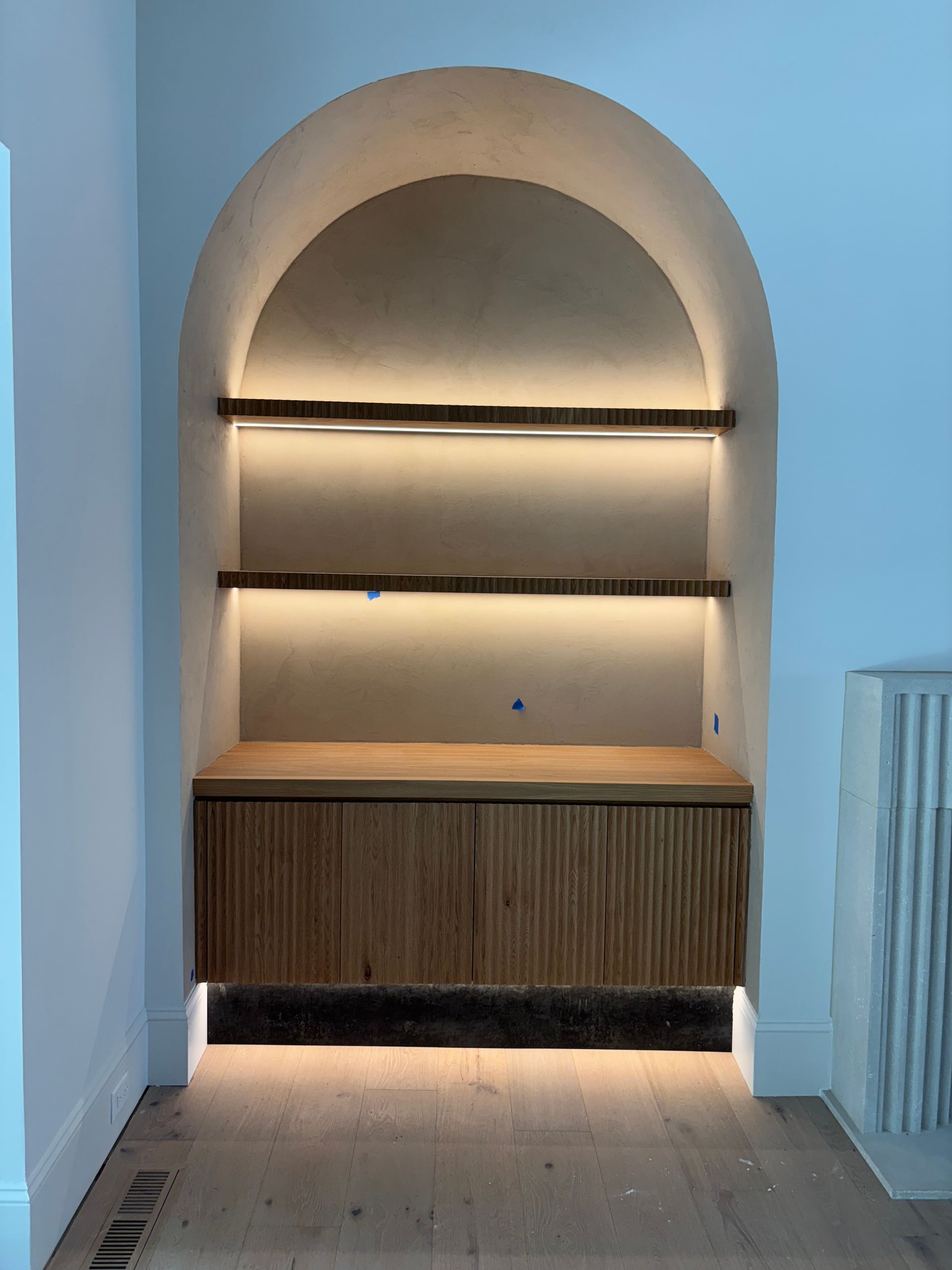 A wooden shelf with a light on it in a room.