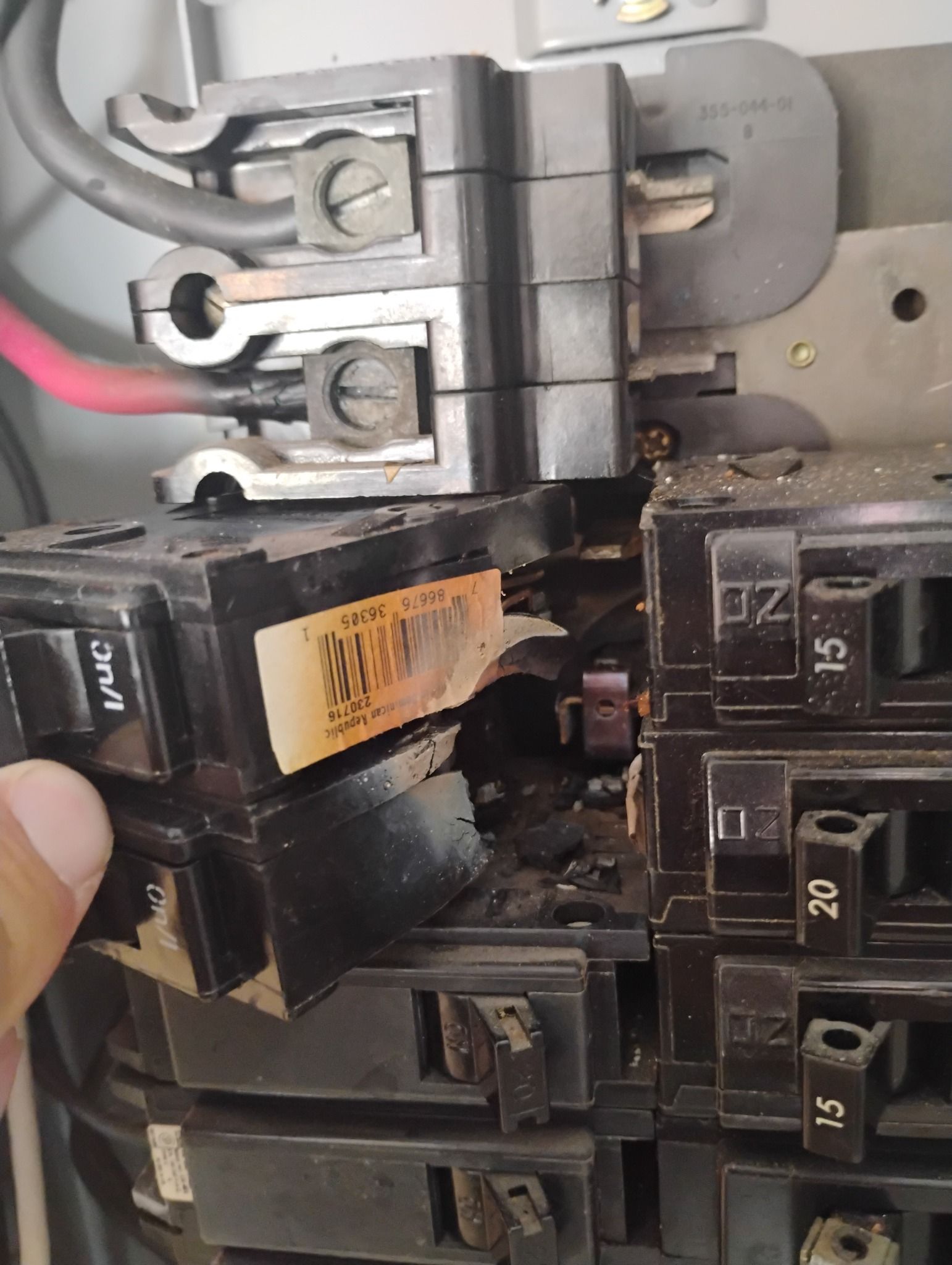 A close up of a person holding a breaker in a electrical box.