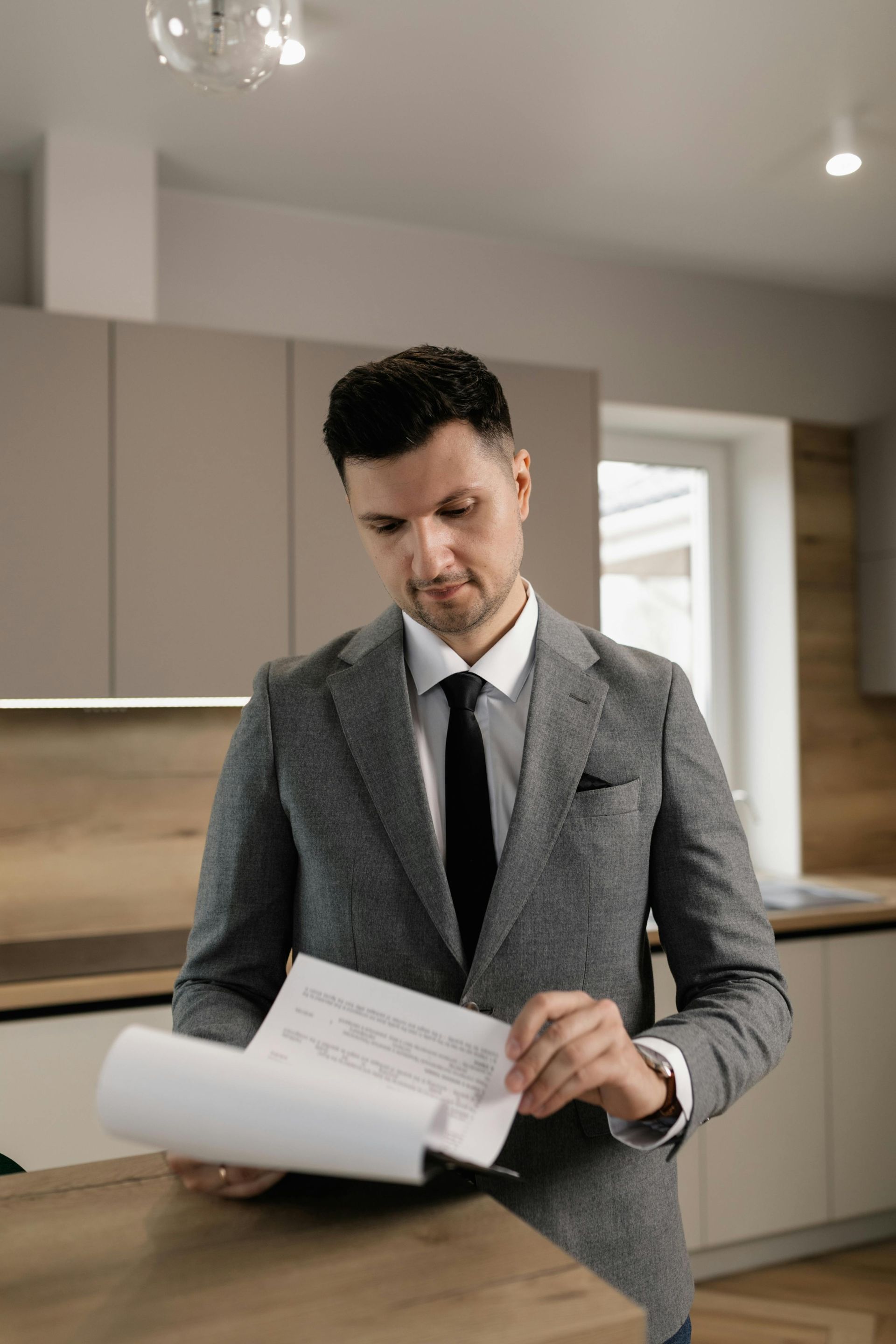 Man in a gray suit reviewing documents in a modern kitchen