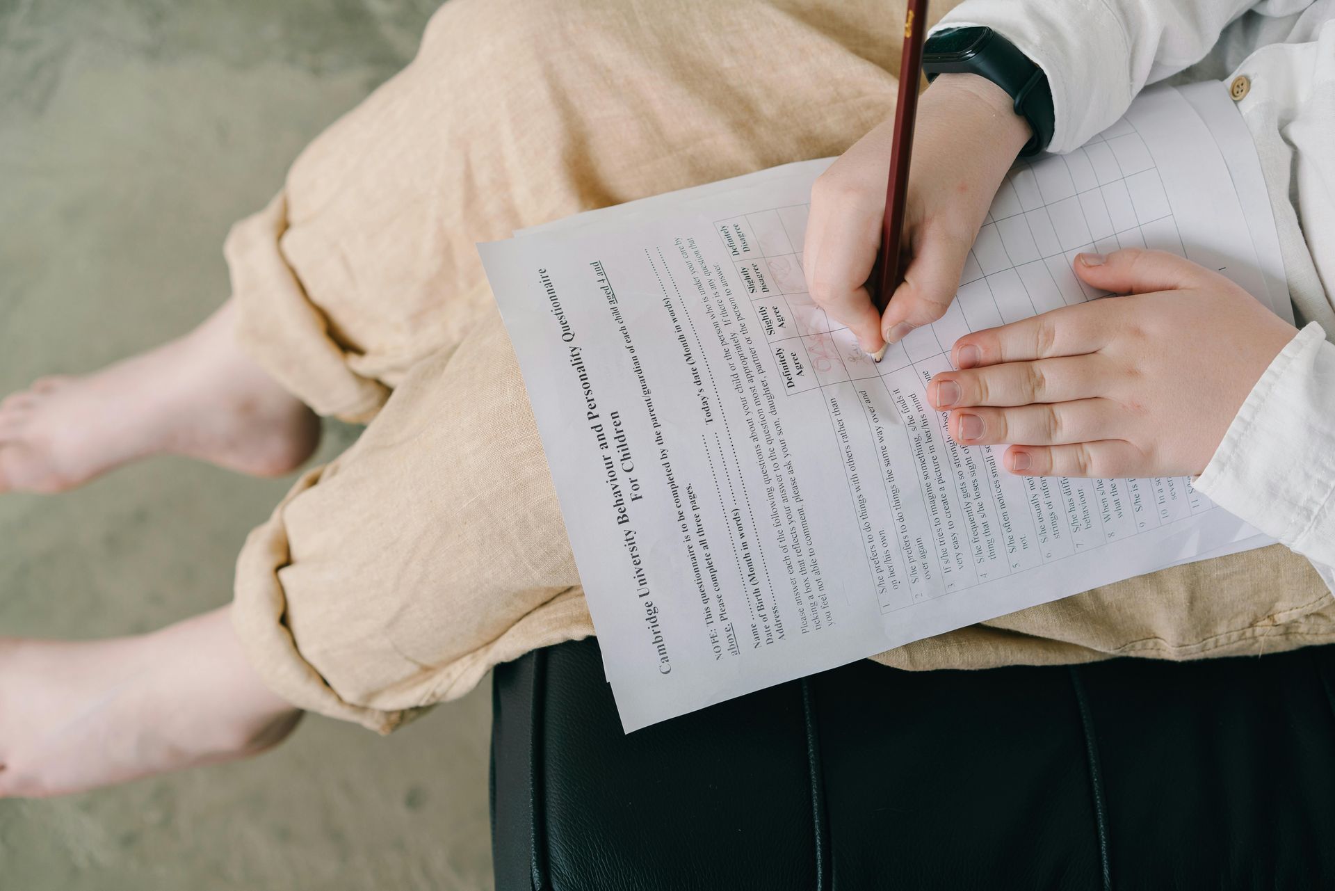 Person writing on a document while seated with bare feet visible