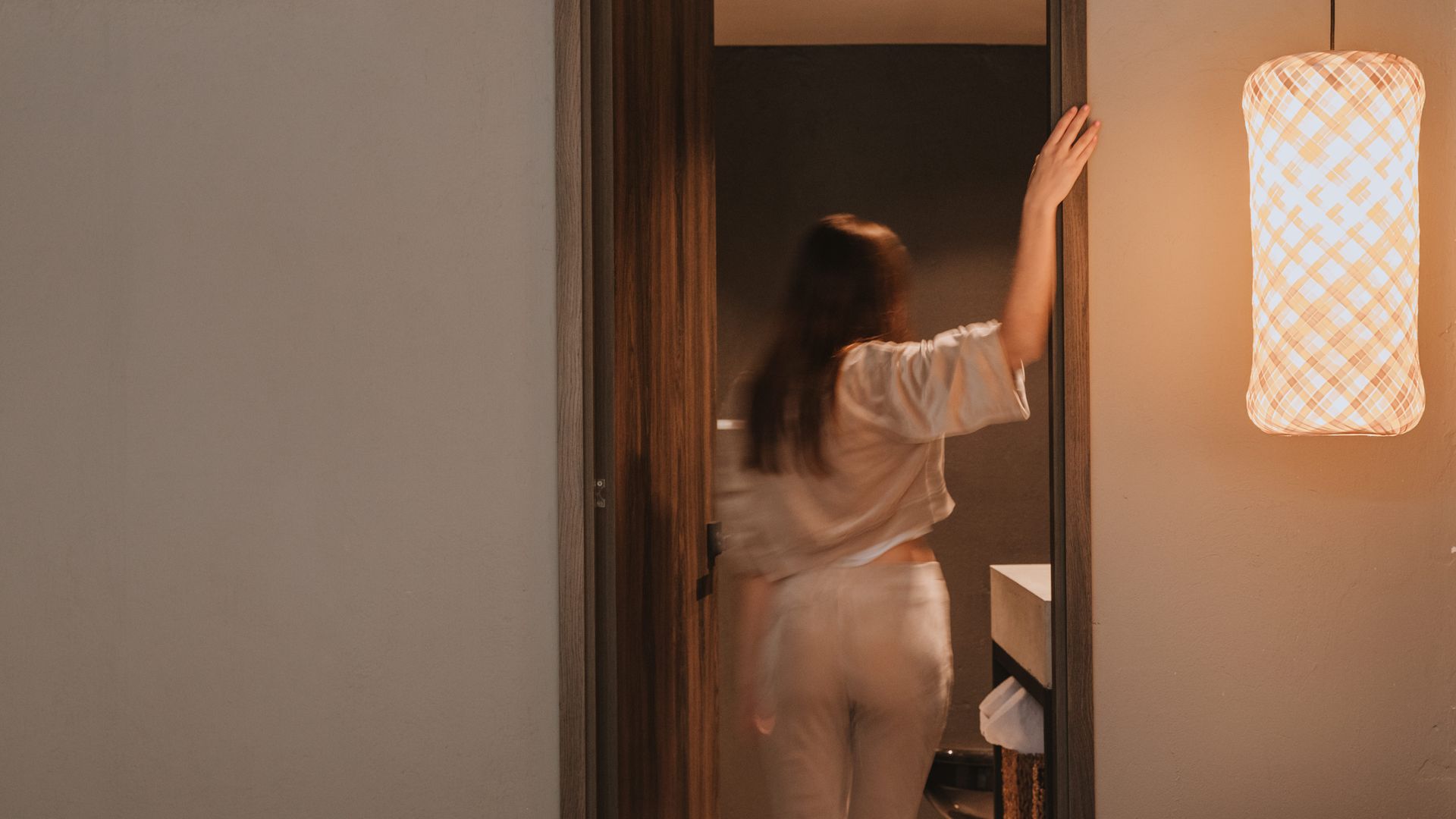 Puerta hacia un baño y una mujer ingresando
