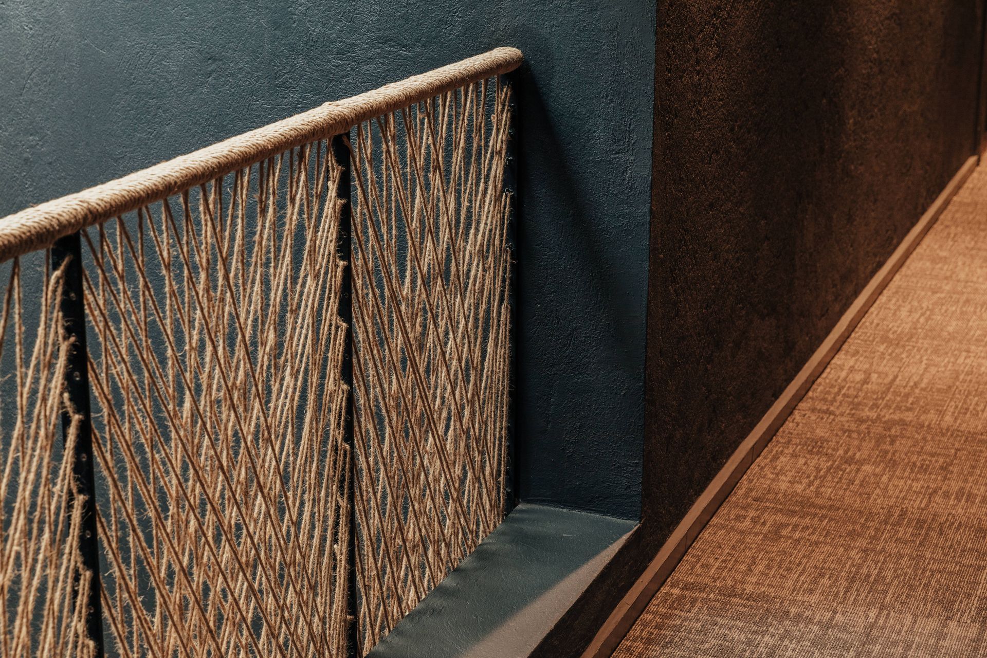 Una barandilla de cuerda en un pasillo con una pared negra.