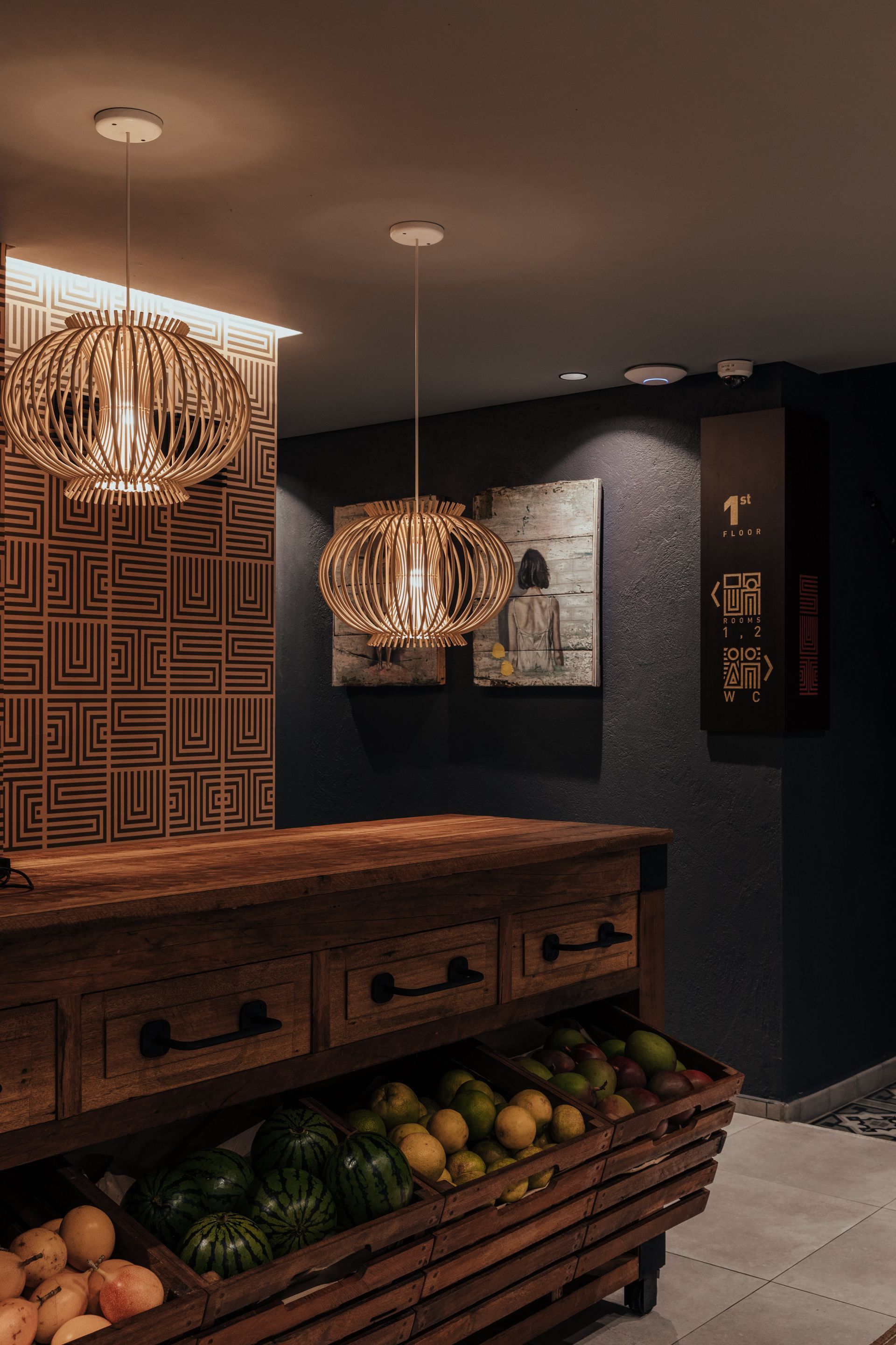 Una habitación con una mesa de madera y cajones llenos de frutas y verduras.