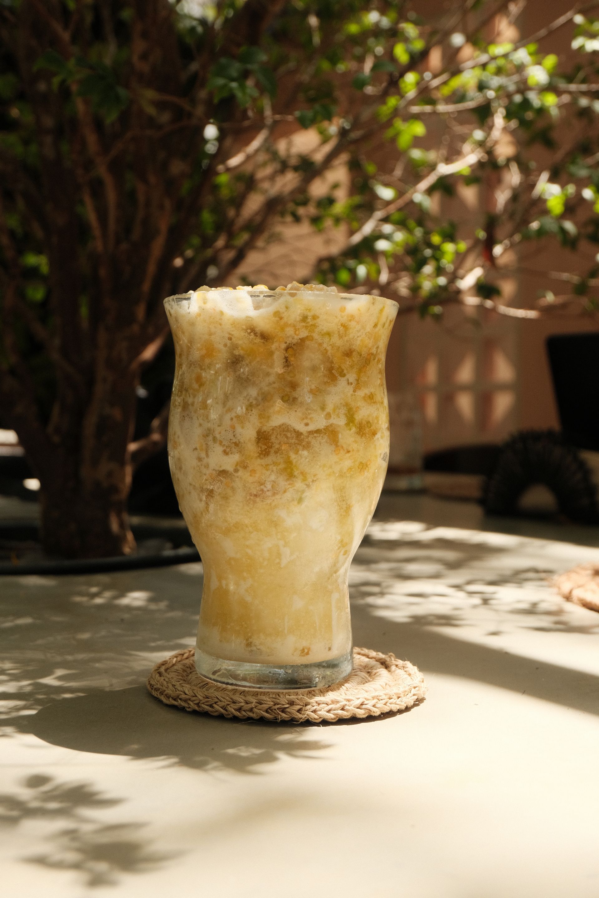 Un vaso de café helado está sobre un posavasos en una mesa.
