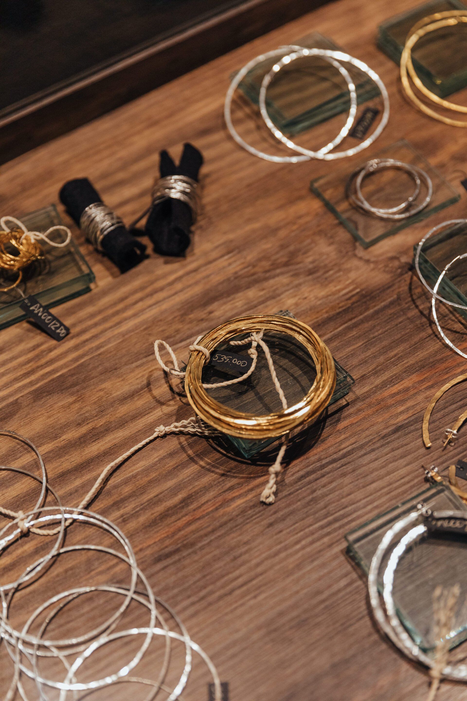 Una mesa de madera cubierta con una variedad de pulseras y anillos.