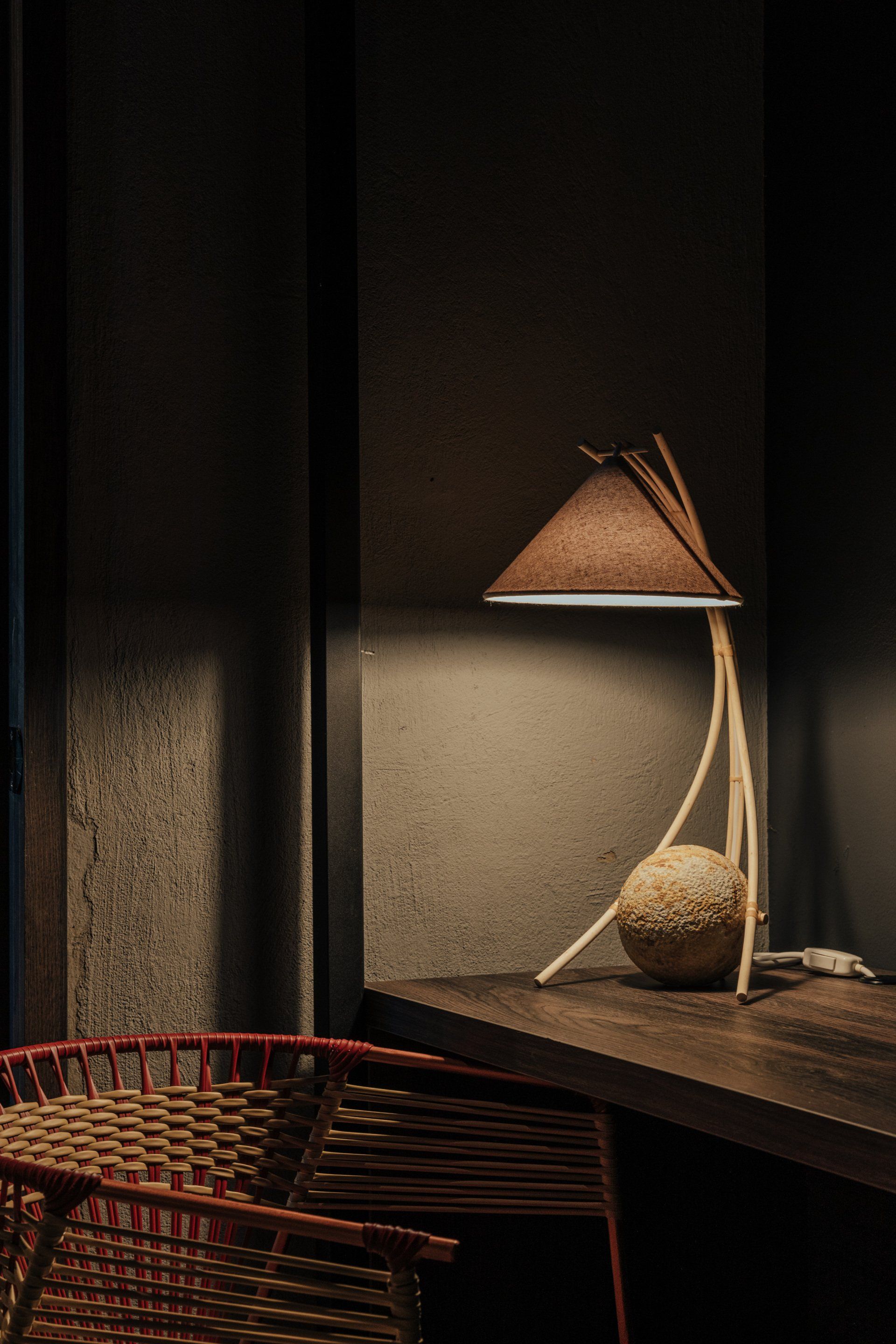 Una lámpara está sobre una mesa de madera al lado de una silla.