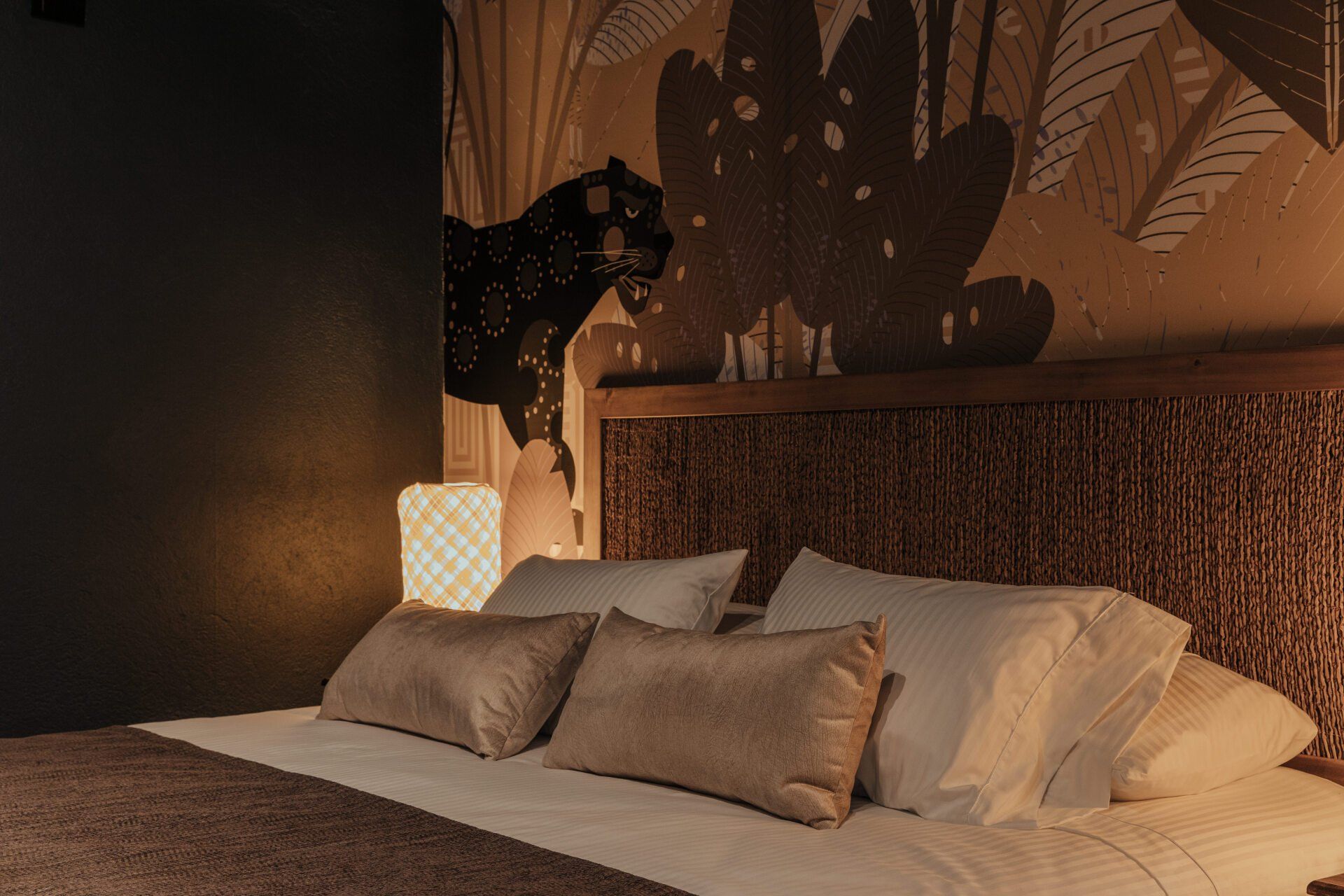 Un dormitorio con una cama, almohadas y una lámpara.