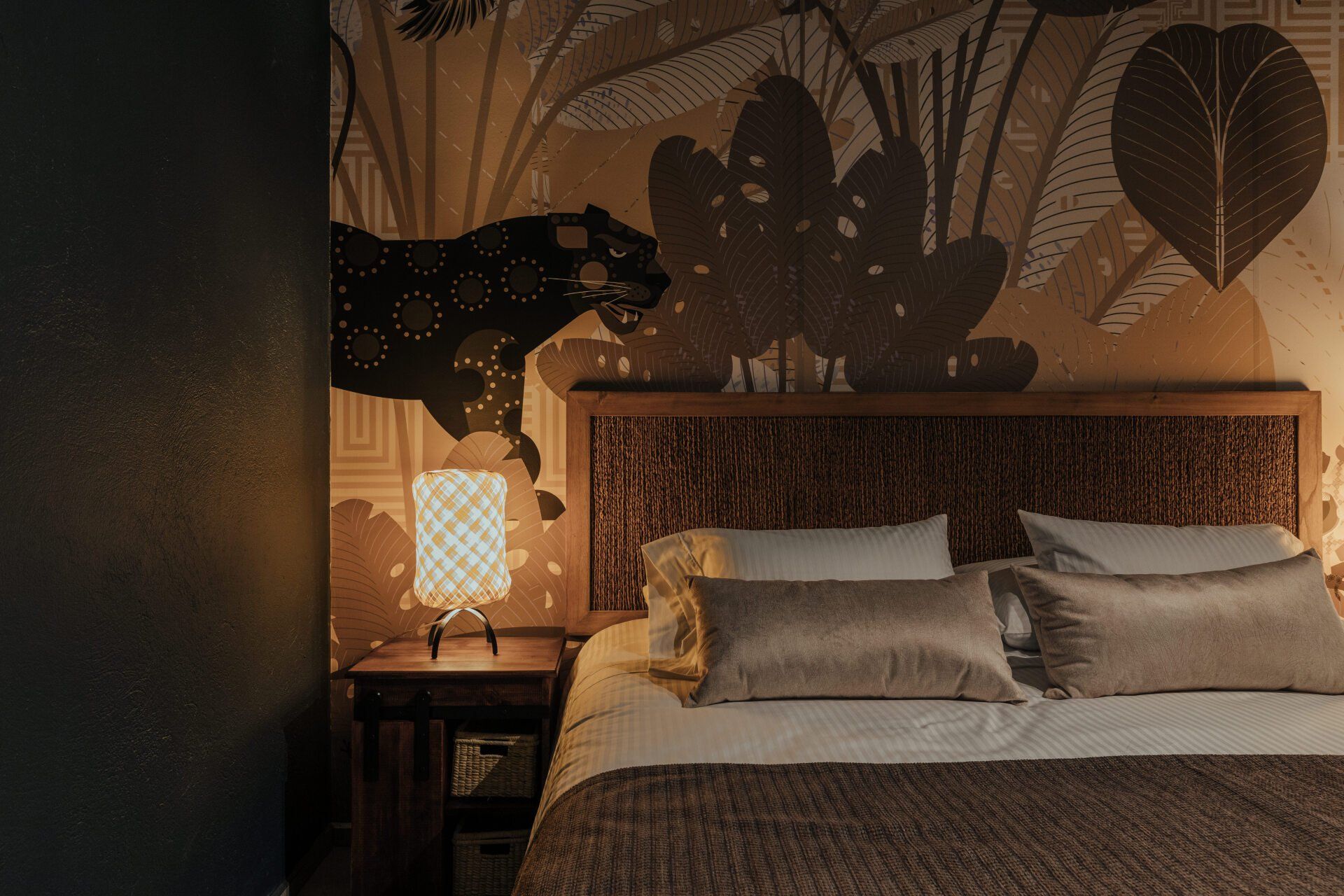 Un dormitorio con una cama, mesita de noche, lámpara y un cuadro en la pared.