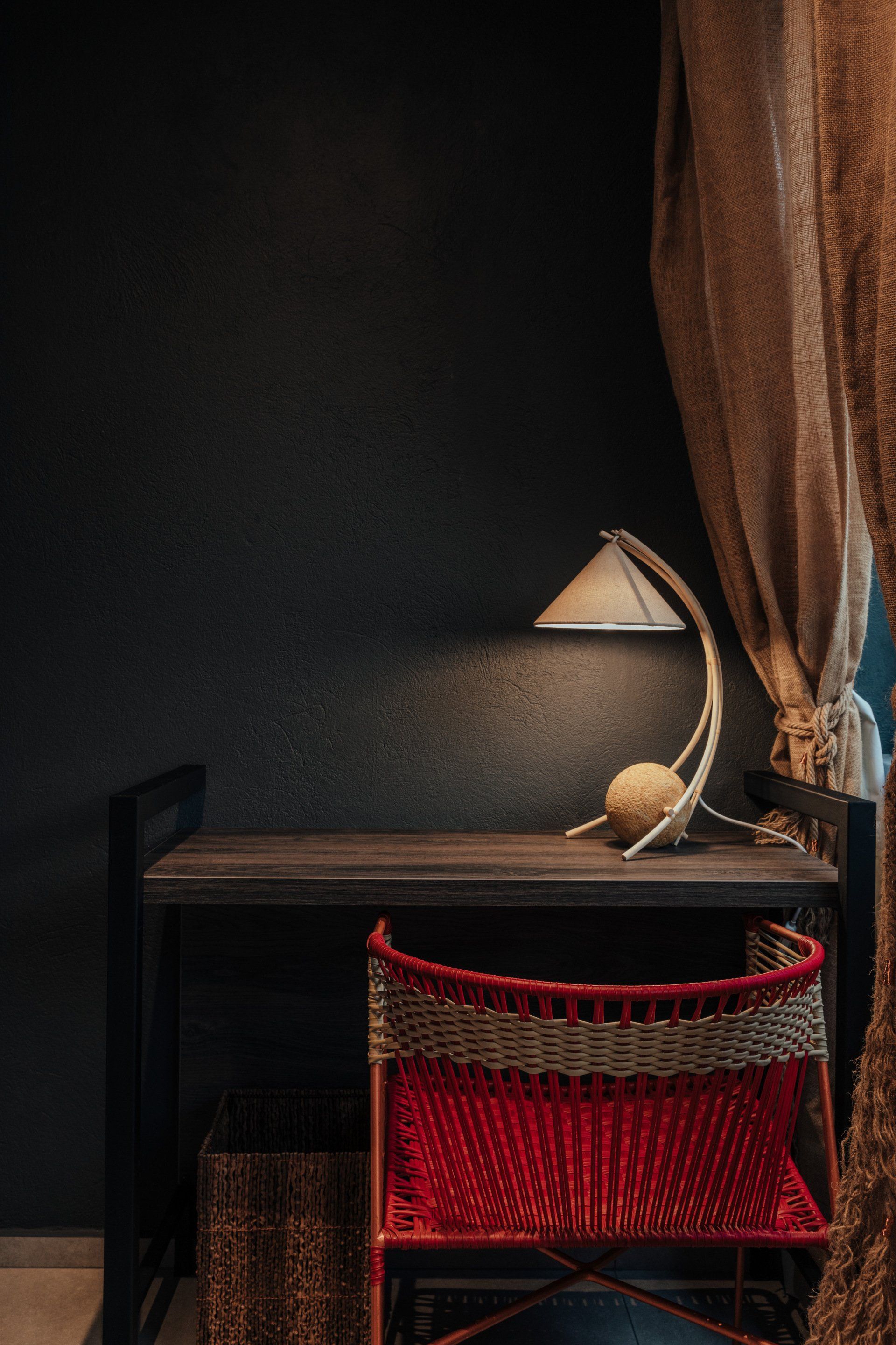 Una silla roja está al lado de un escritorio de madera con una lámpara encima.