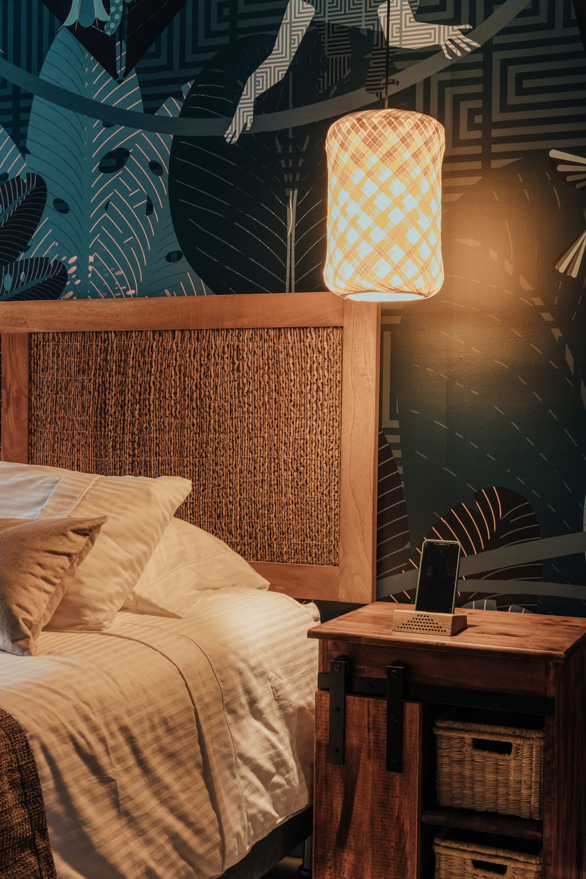 Un dormitorio con una cama, mesita de noche y lámpara.