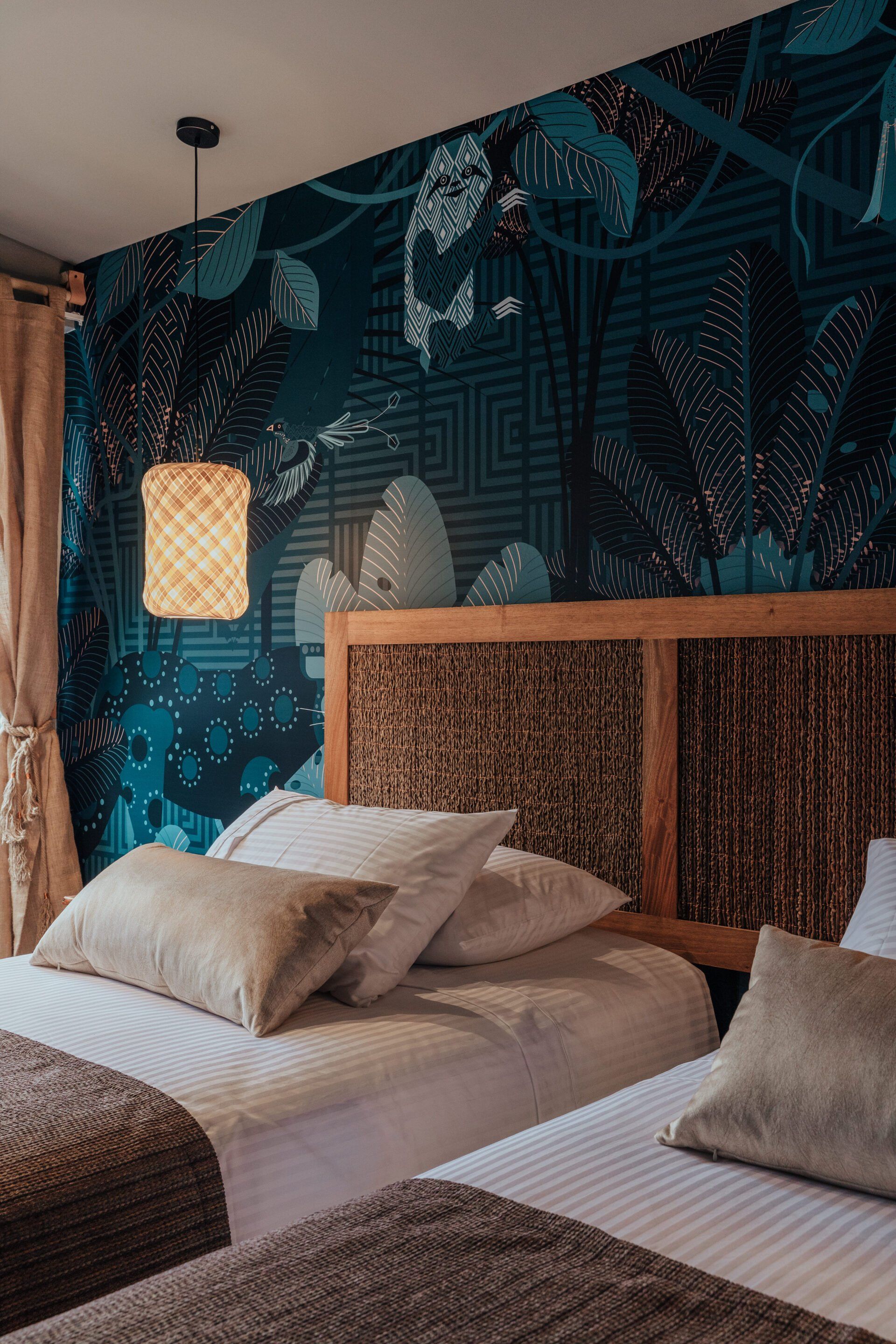 Un dormitorio con dos camas, una lámpara y un mural en la pared.