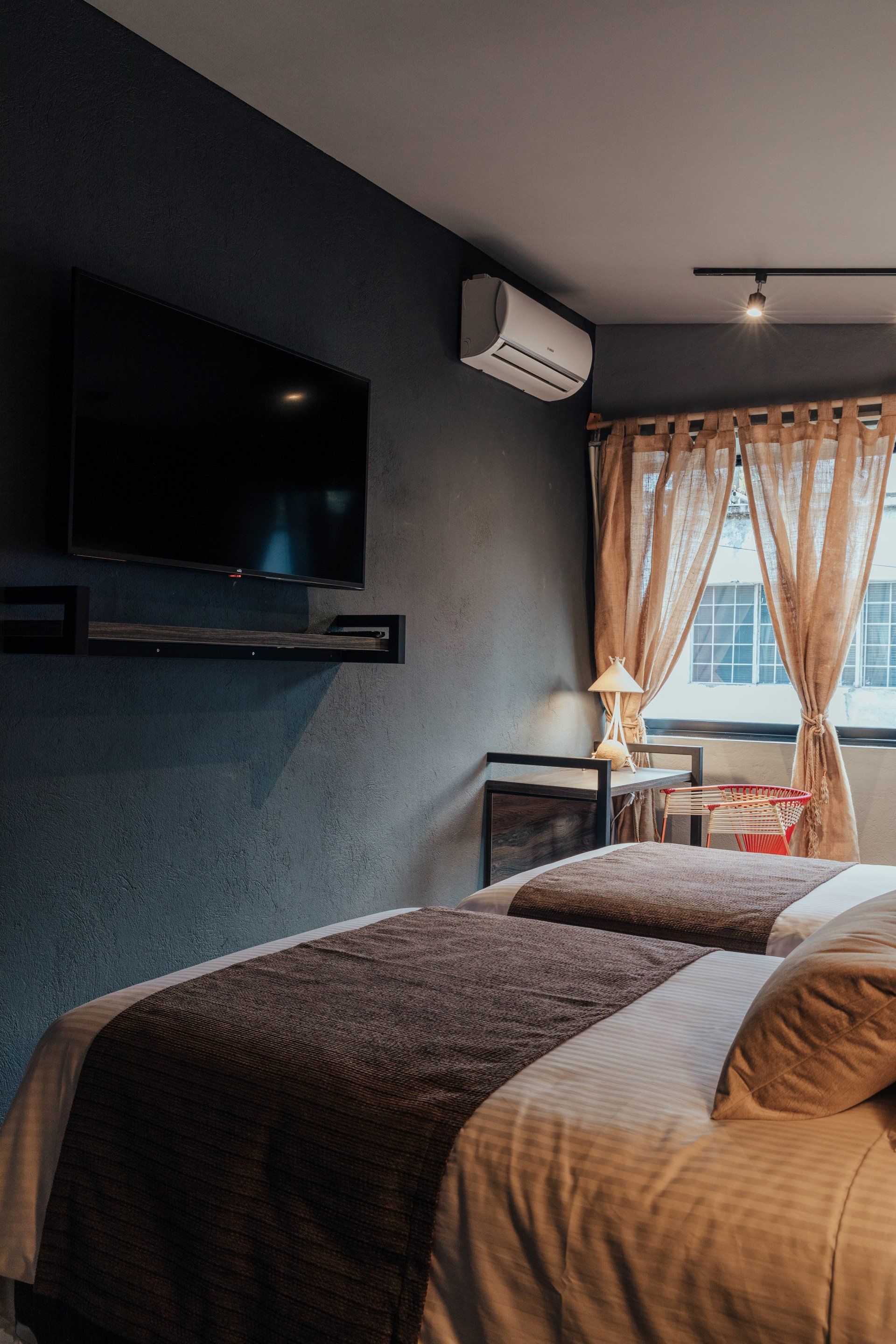 Una habitación de hotel con dos camas, un televisor y una ventana.