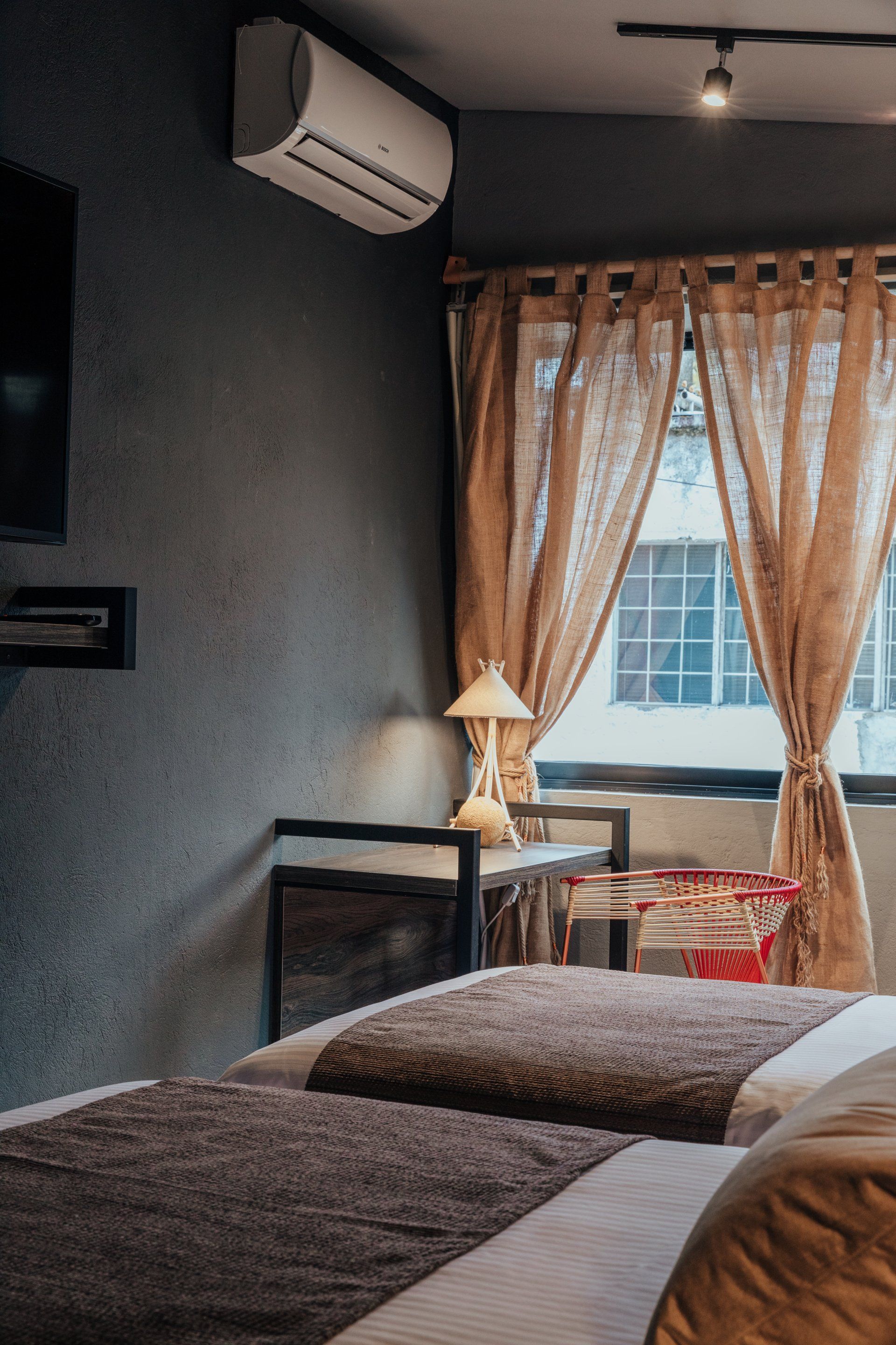 Un dormitorio con dos camas, un televisor, una mesa y una ventana.