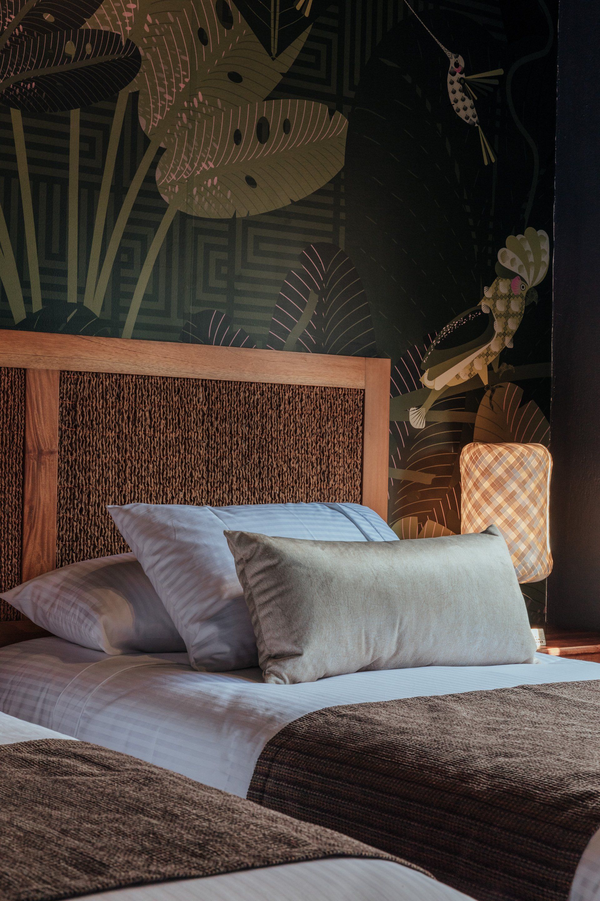 Un dormitorio con dos camas, un cabecero de madera y un papel pintado floral.