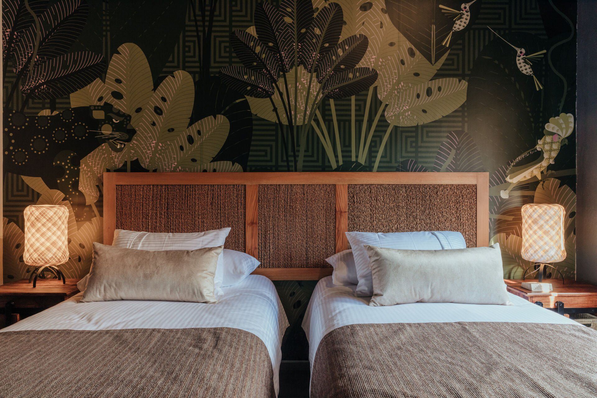 Hay dos camas en una habitación de hotel con un papel tapiz floral en la pared.