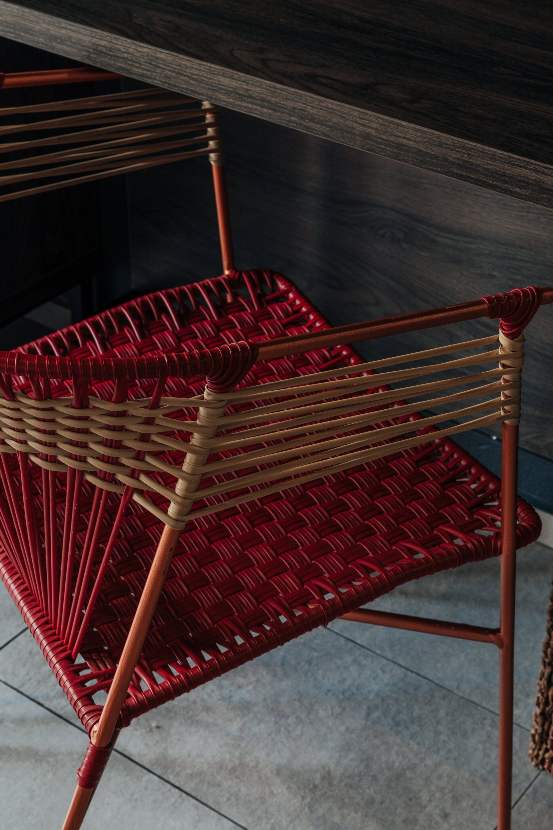 Una silla de mimbre roja está debajo de una mesa de madera.
