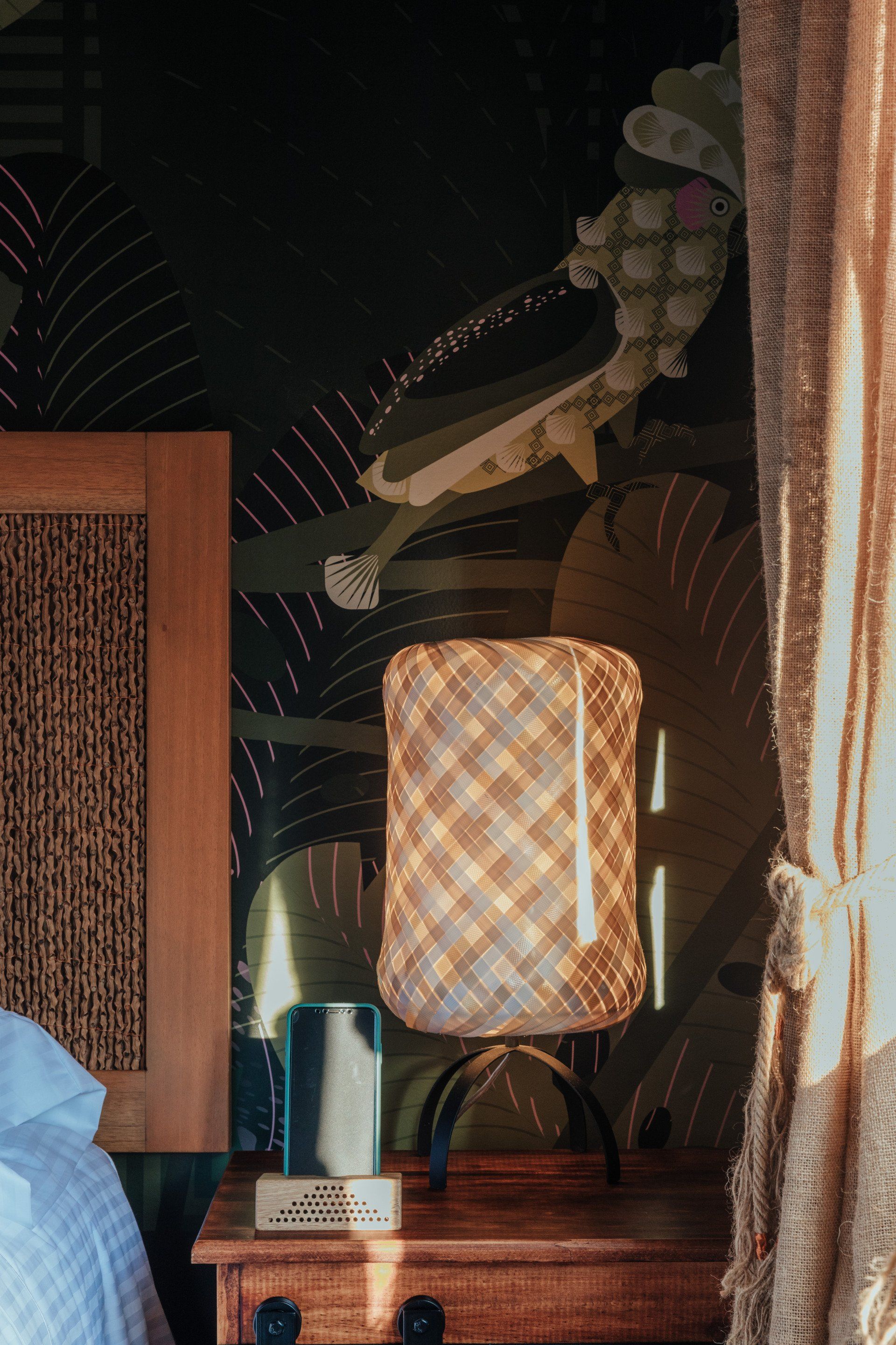 Una lámpara está colocada en una mesita de noche al lado de una cama.