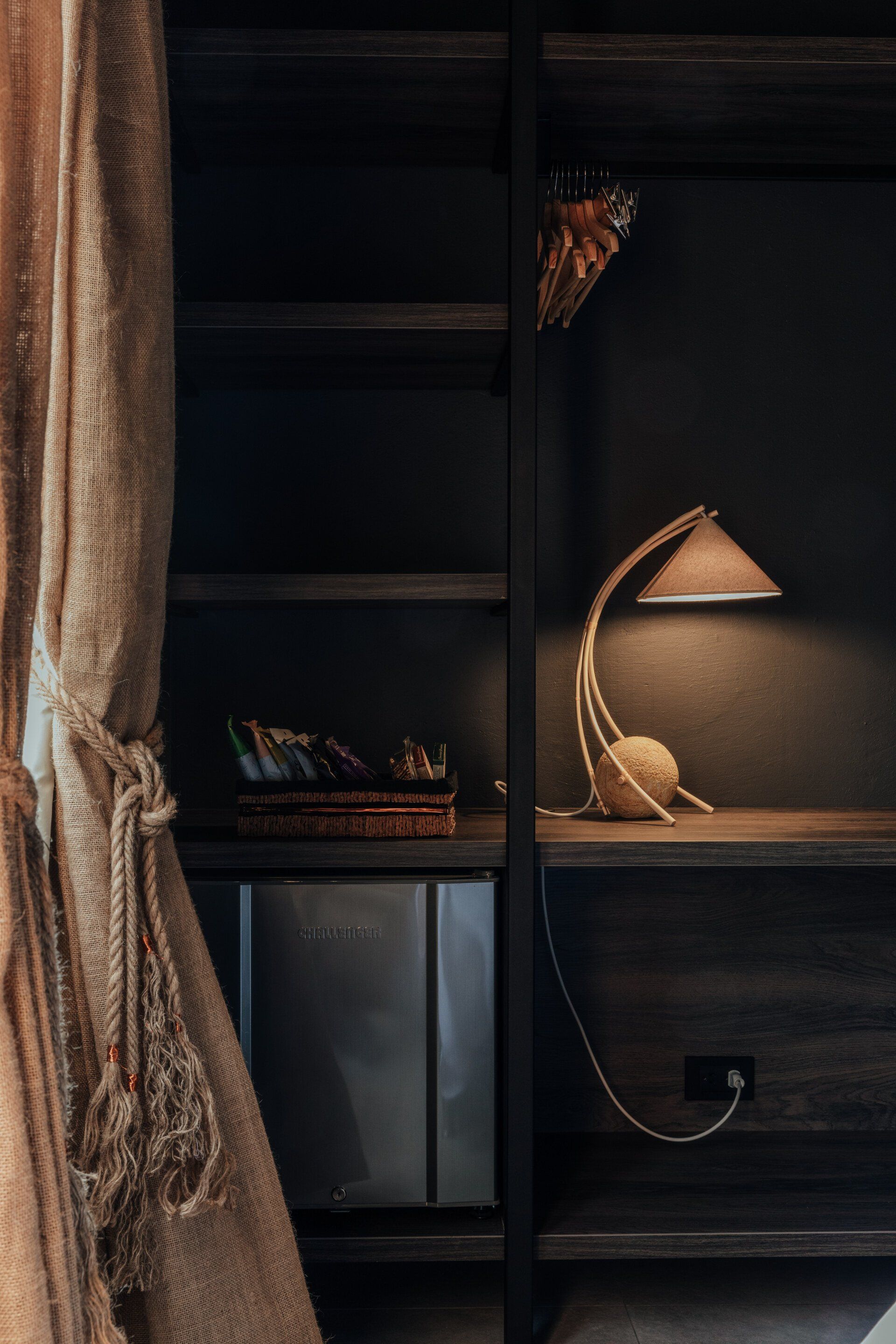 Una lámpara está sobre una mesa al lado de un estante en una habitación.