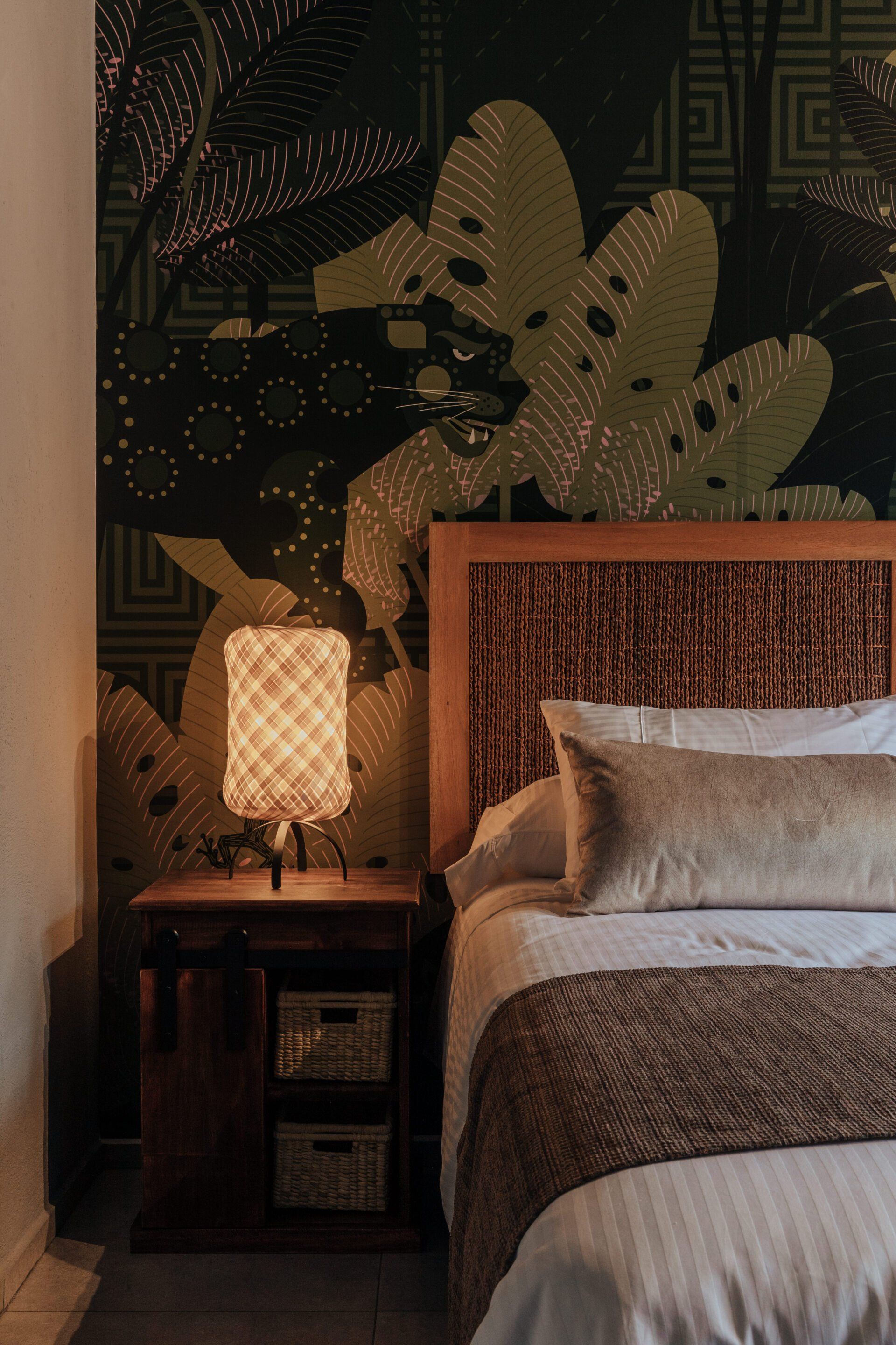 Un dormitorio con cama, mesita de noche y lámpara.