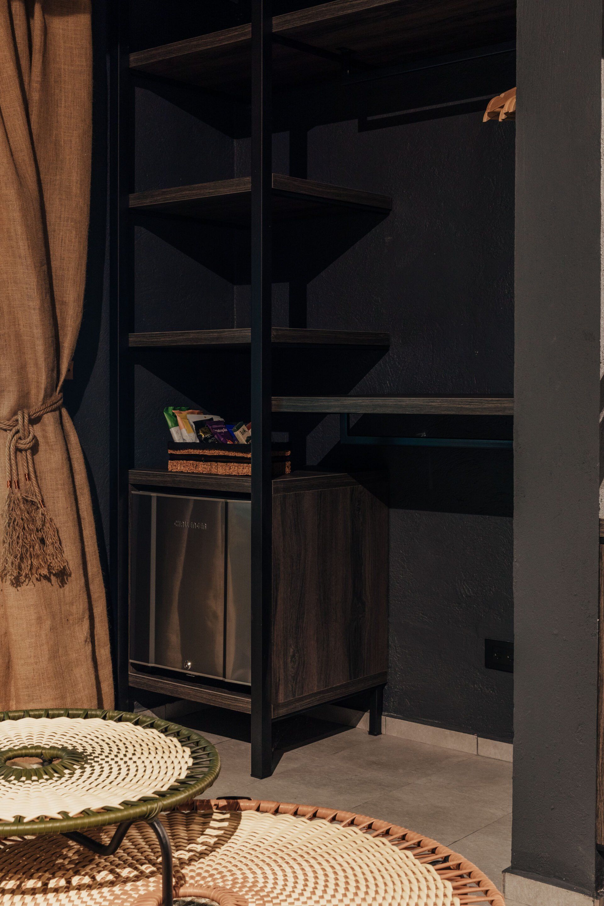 Una habitación con una mesa, estantes y un refrigerador.