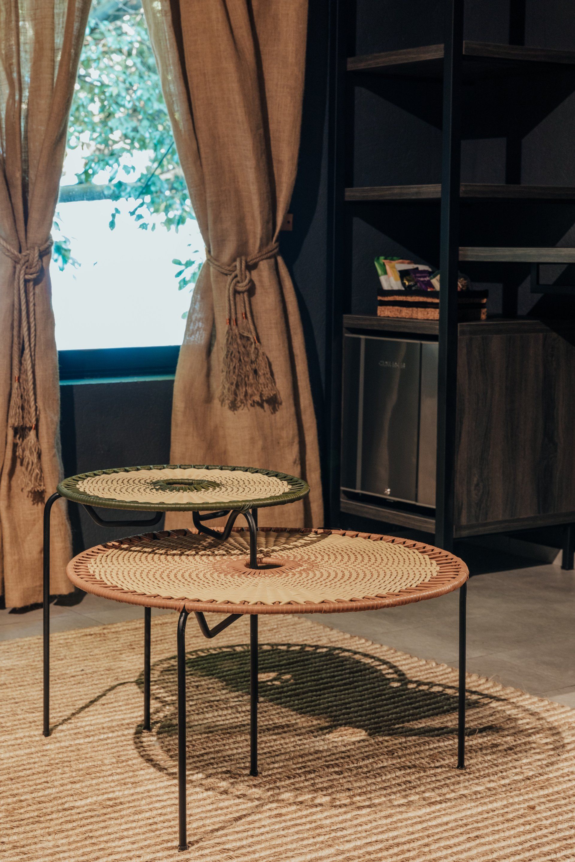 Dos mesas de café están colocadas sobre una alfombra en una sala de estar al lado de una ventana.