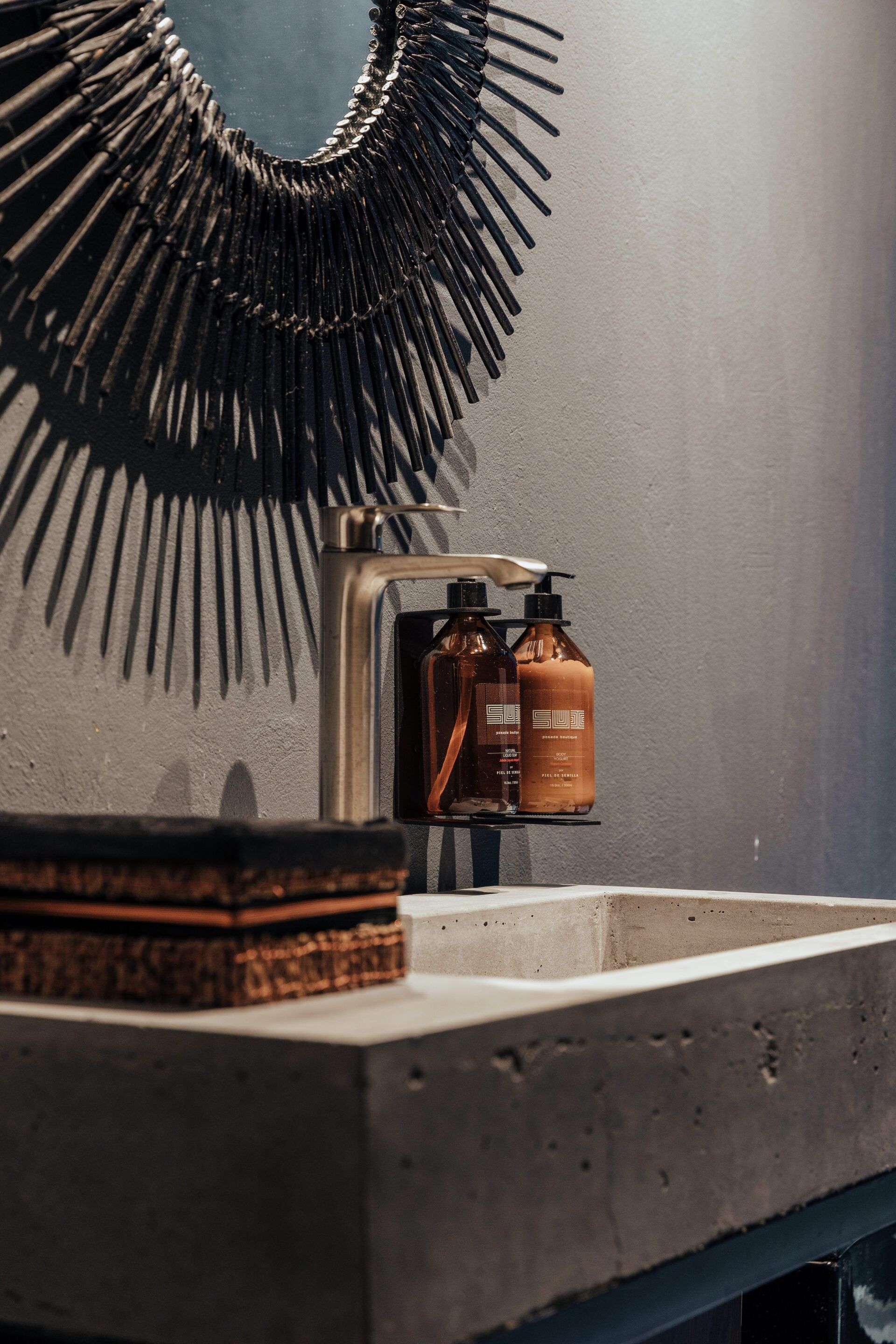 Un lavabo de baño con dos botellas de jabón y un espejo.