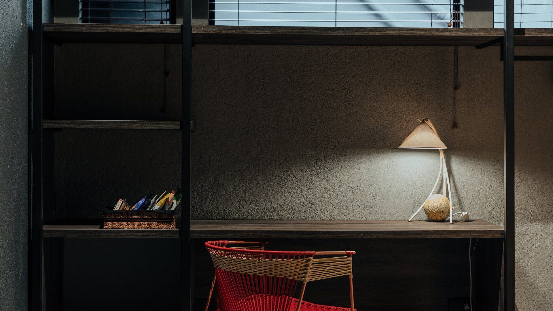 Hay un escritorio con una silla y una lámpara encima.