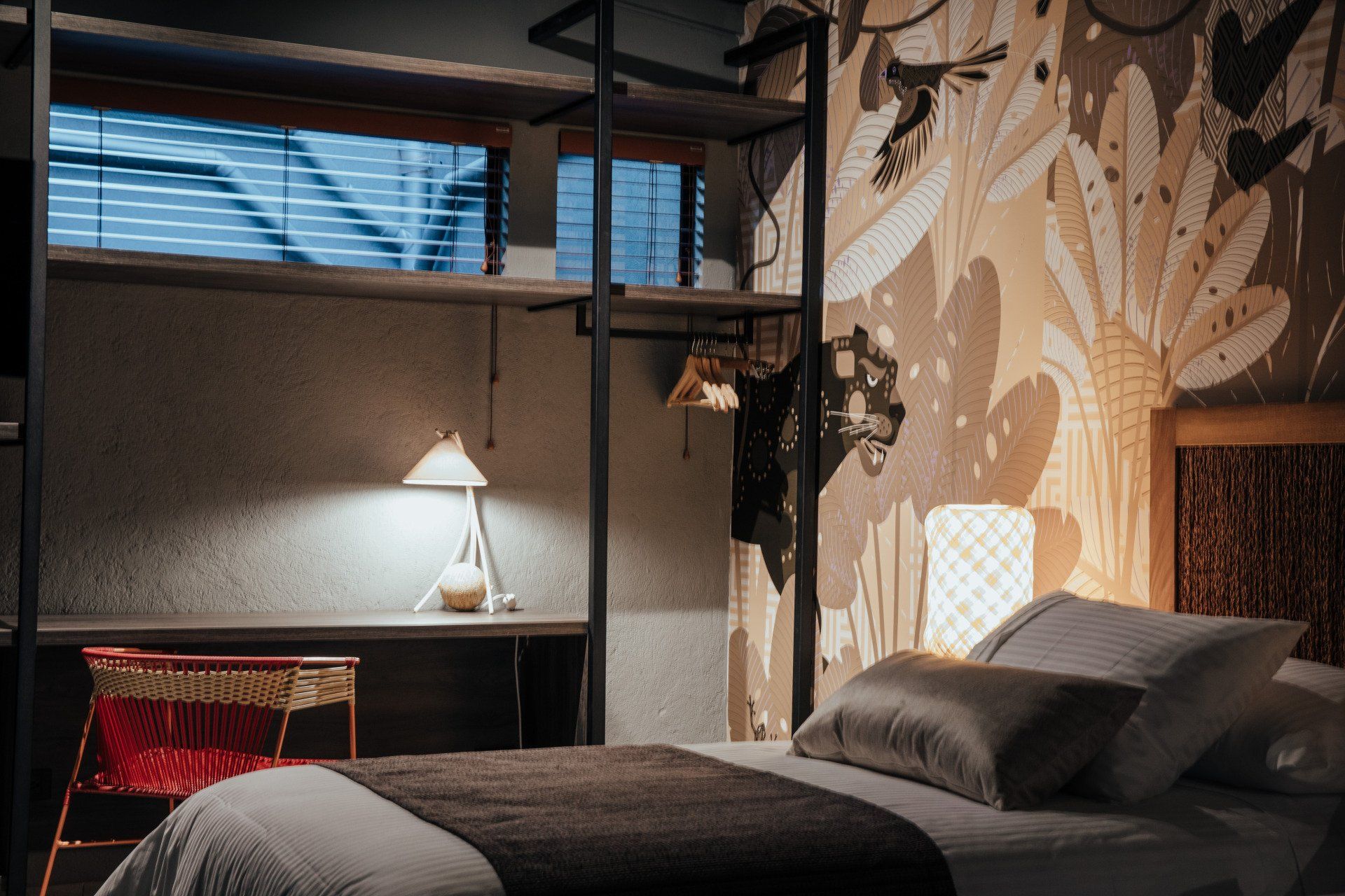 Un dormitorio con una cama, escritorio, lámpara y silla.