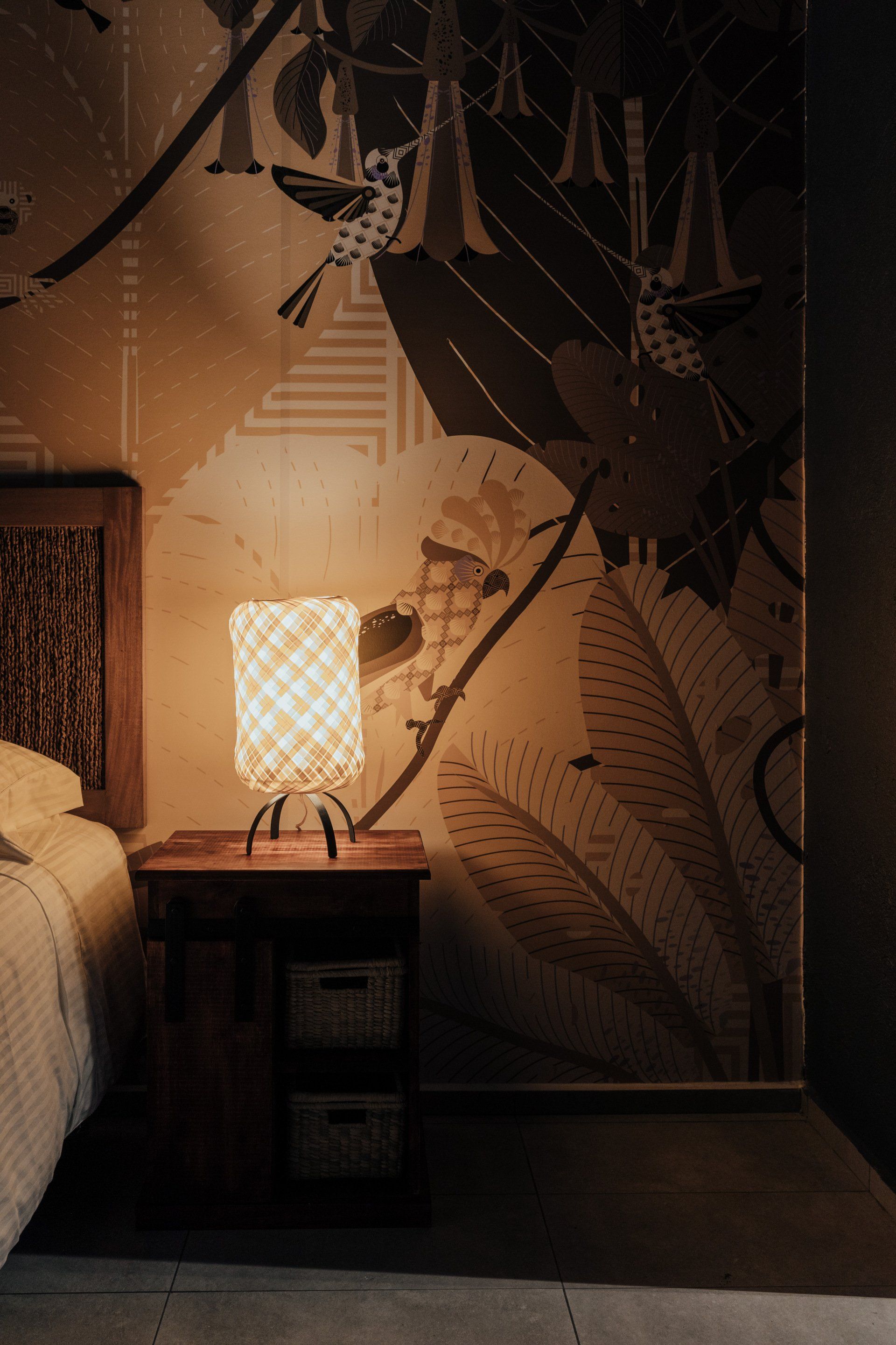 Un dormitorio con una lámpara en una mesita de noche al lado de una cama.