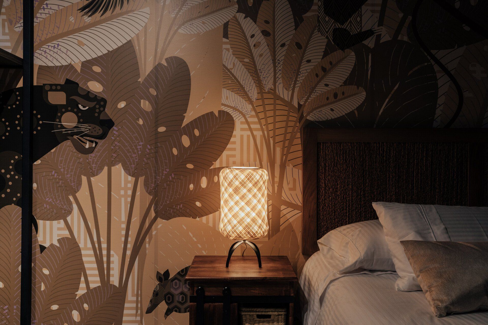 Un dormitorio con una cama, mesita de noche y lámpara.