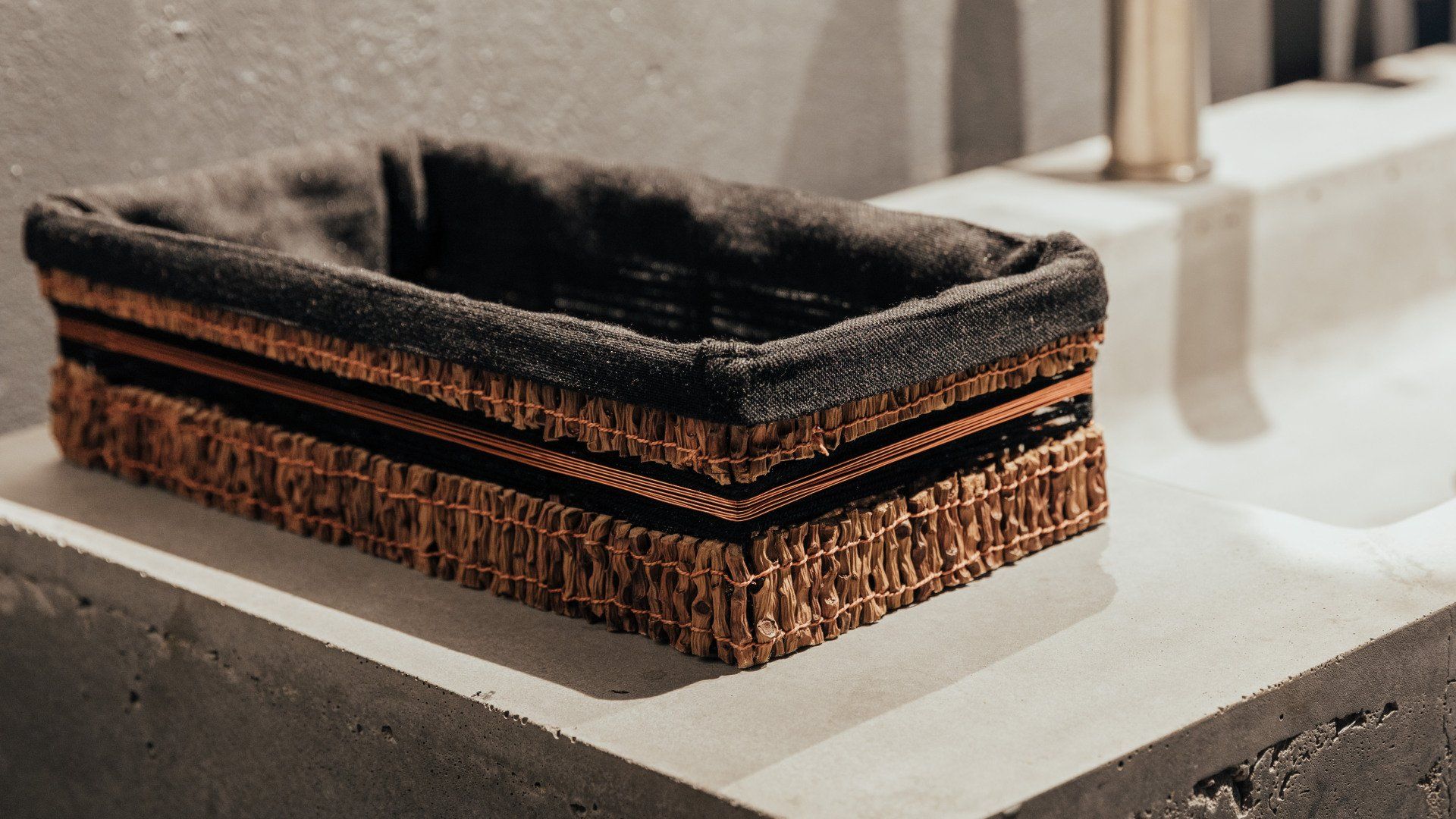 Hay una canasta sobre un mostrador al lado de un fregadero.