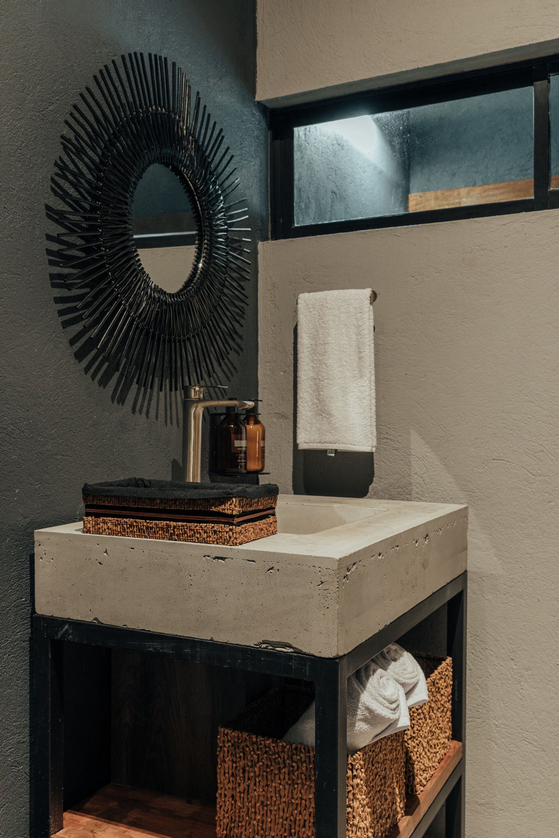 Un baño con lavabo, espejo y cestas de mimbre.